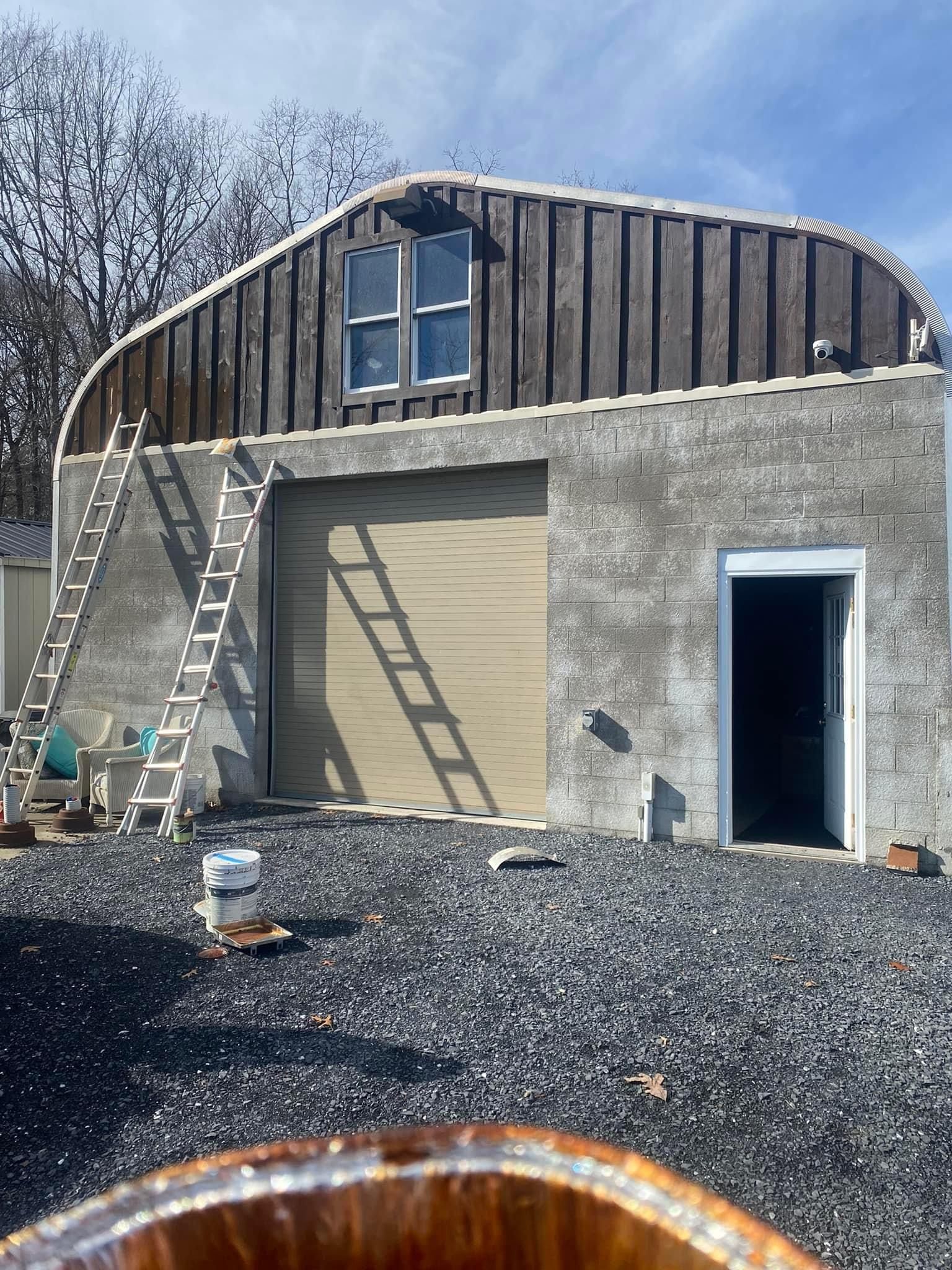 A large building with a garage door and a ladder in front of it — KP's Home Repair — McGaheysville, VA
