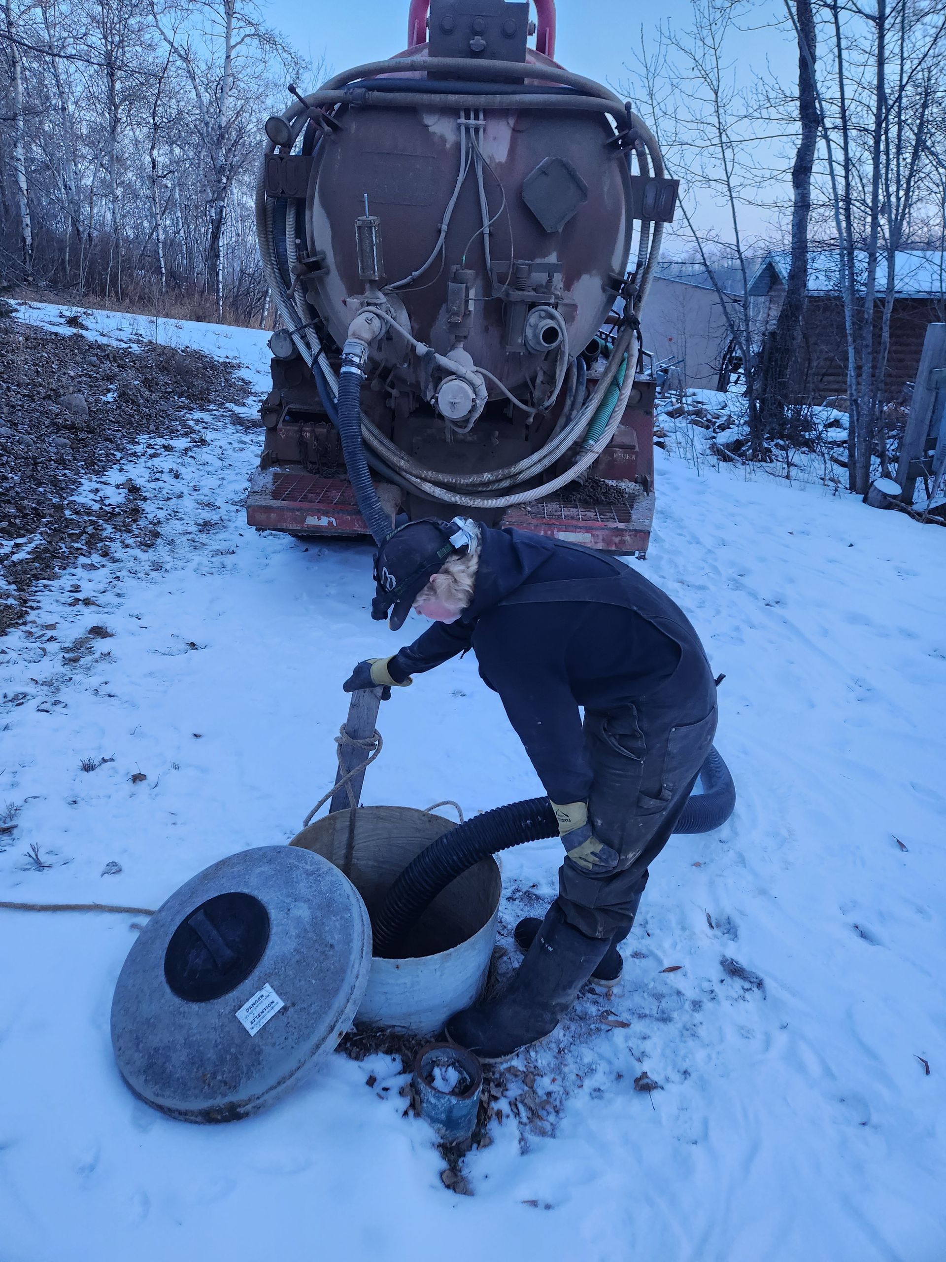 A man is working on a septic tank in the snow.