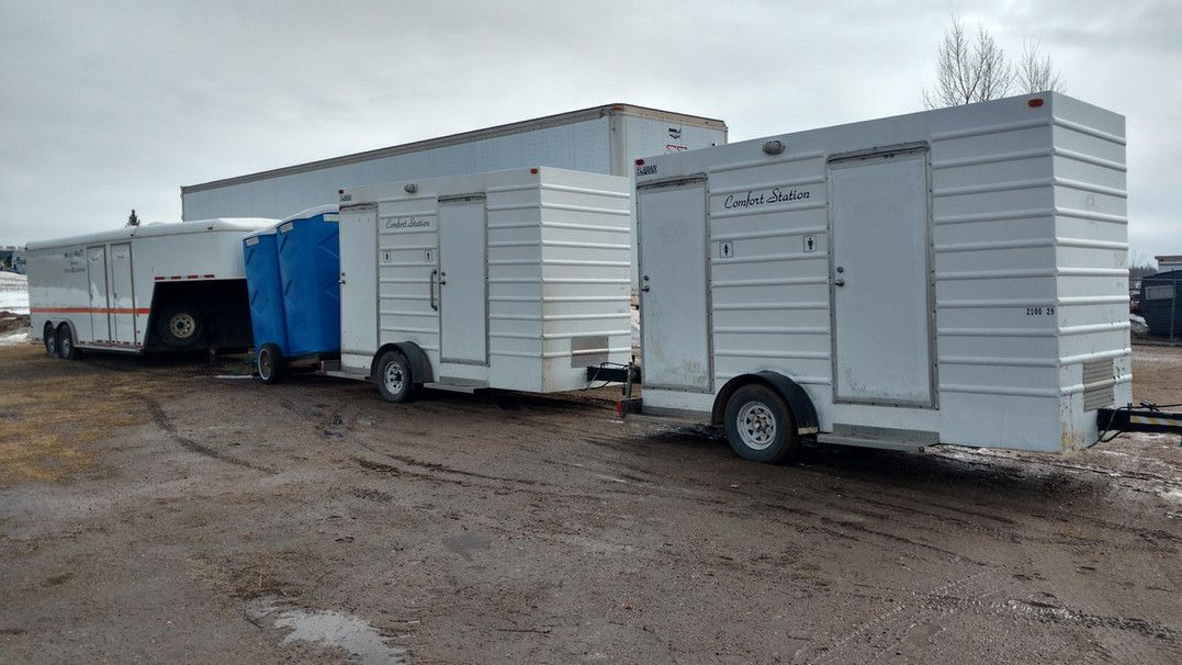 Three trailers are parked next to each other in a dirt field.