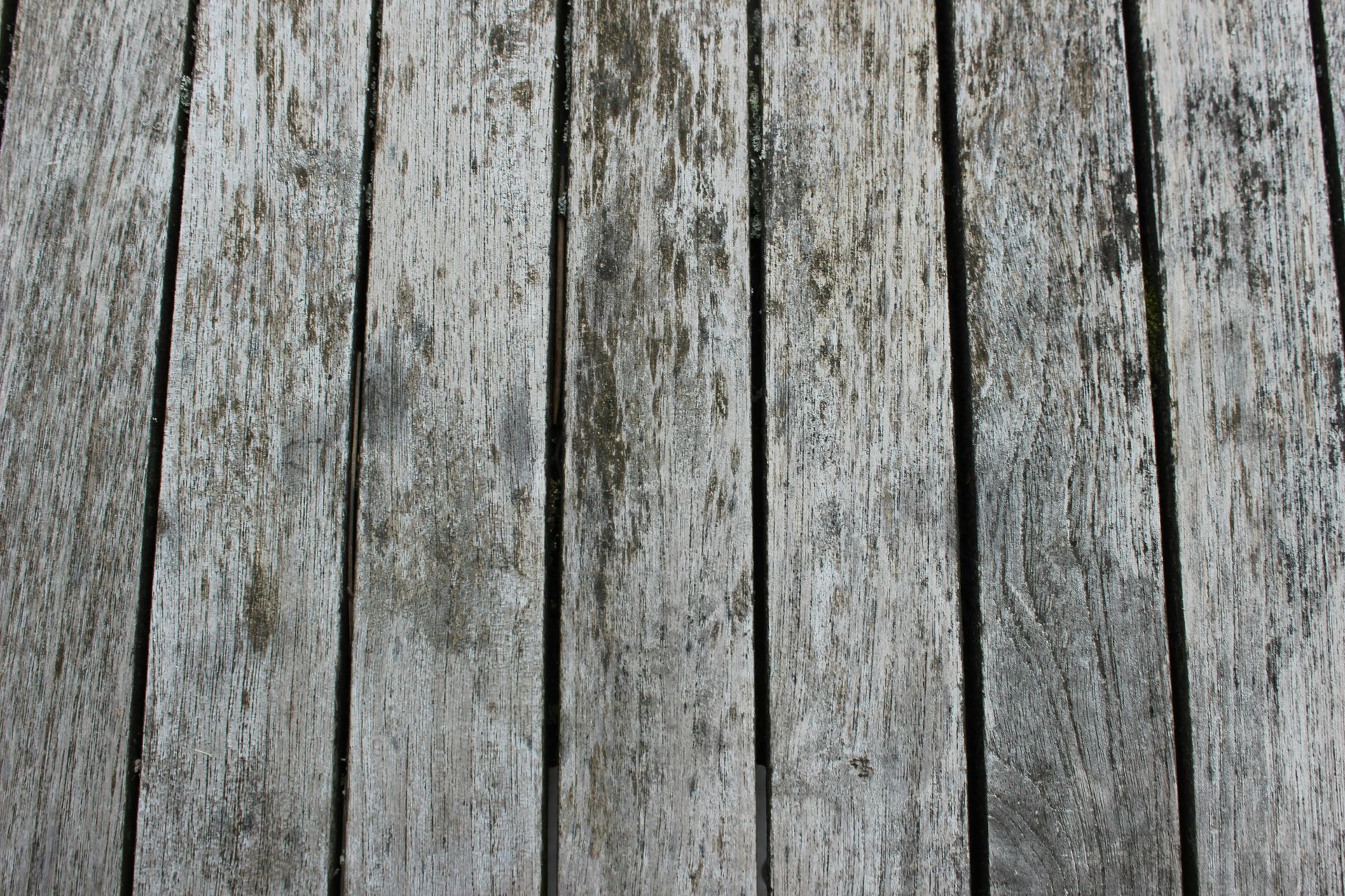 Weathered, grey wooden planks arranged vertically, showing texture and age.