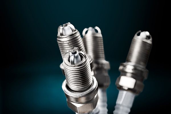 Three spark plugs are sitting next to each other on a black background. | Autotrends - Irving Park