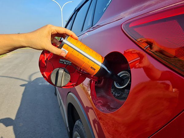 A person is pouring gas into a red car | Autotrends - Irving Park