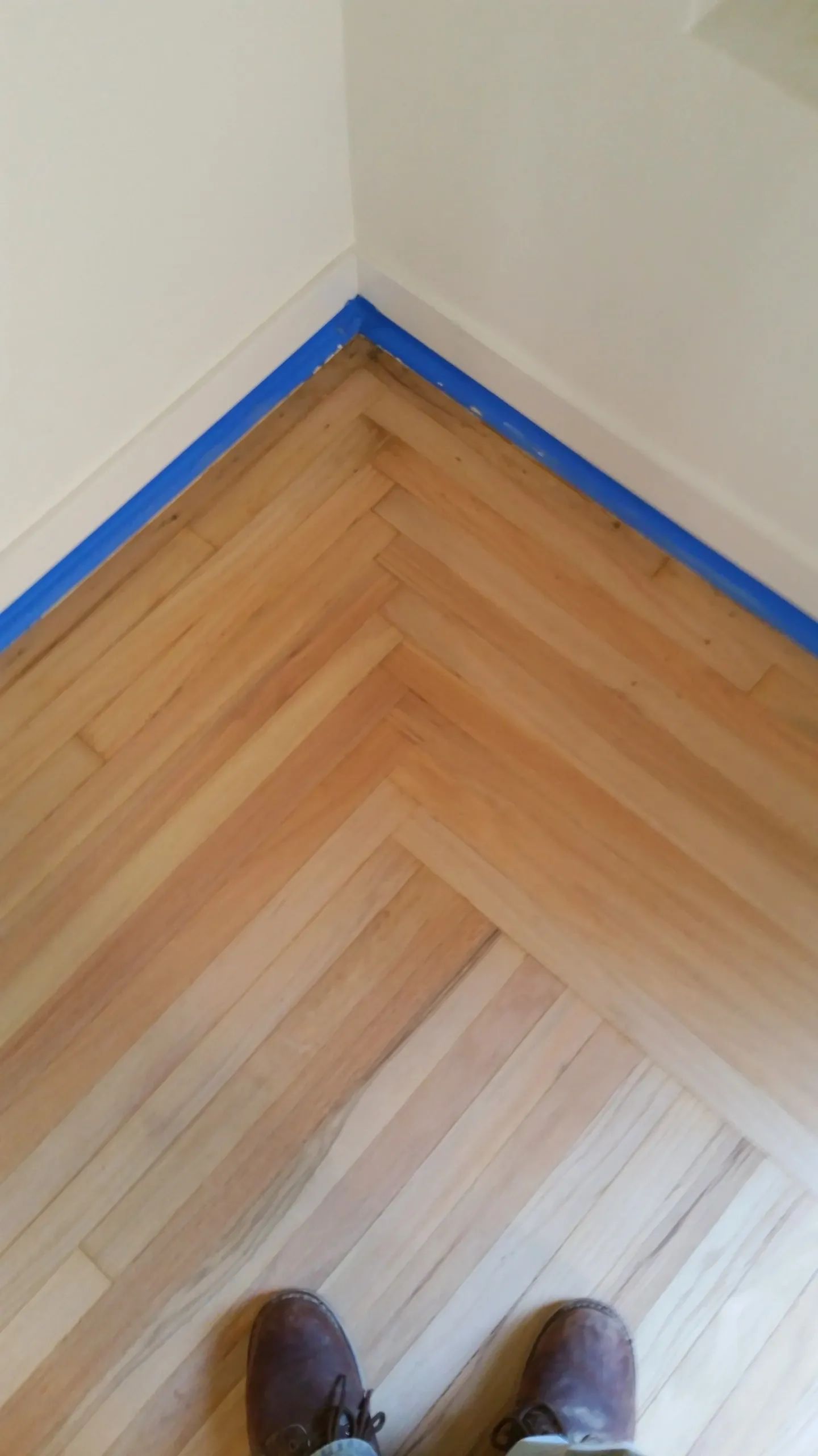 A person is standing on a wooden floor in a room