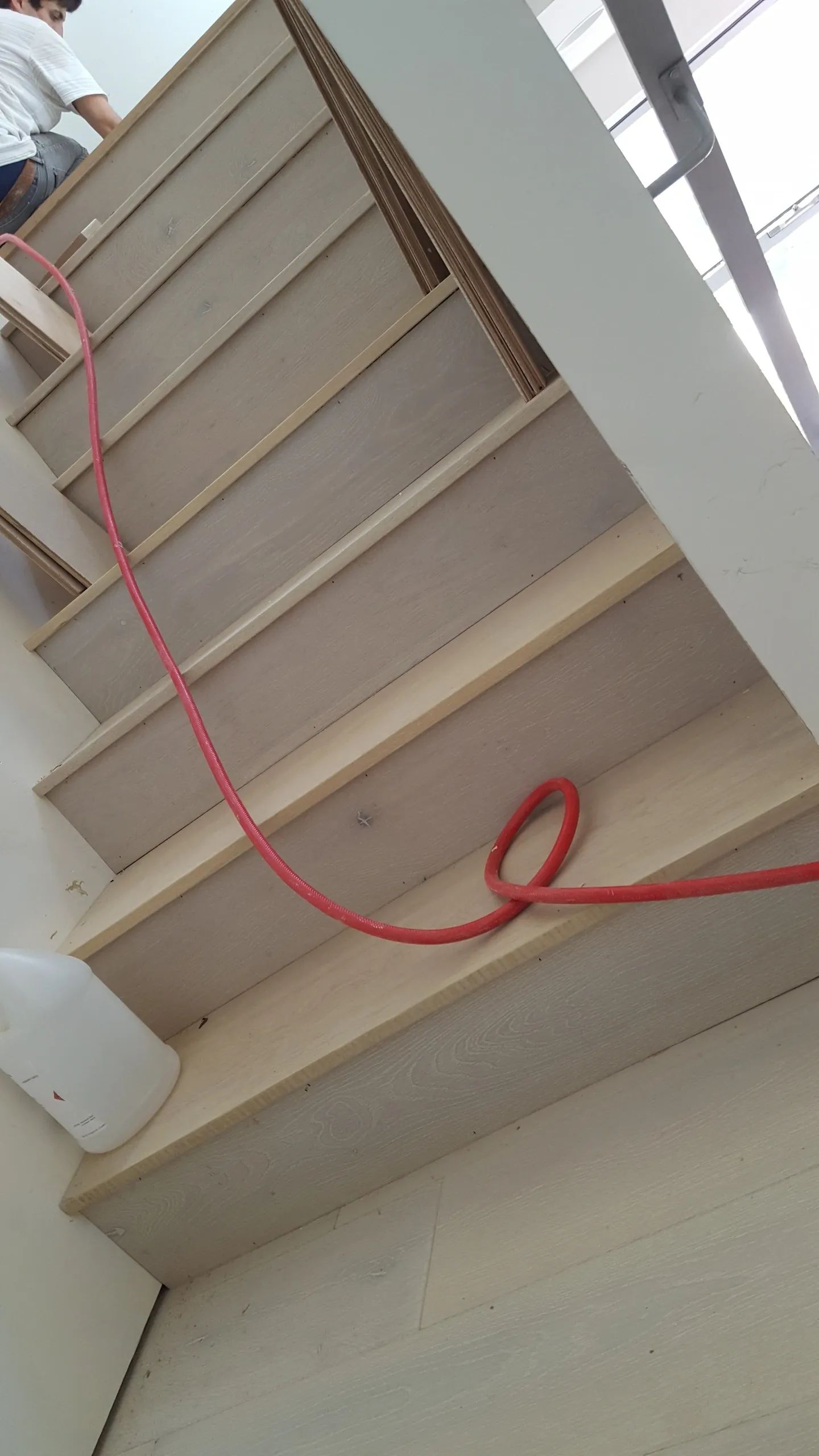 A red hose is hanging from the side of a staircase