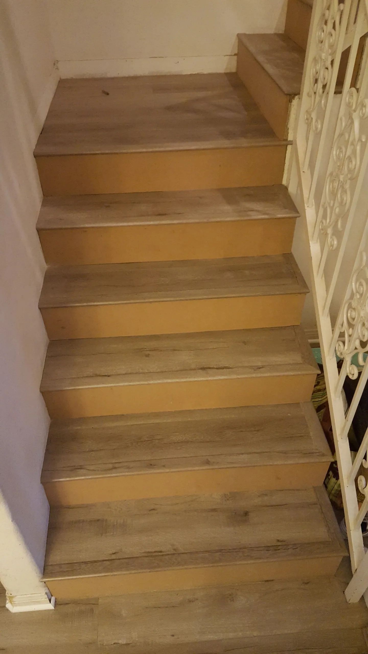 A set of stairs with a wooden floor and a white railing
