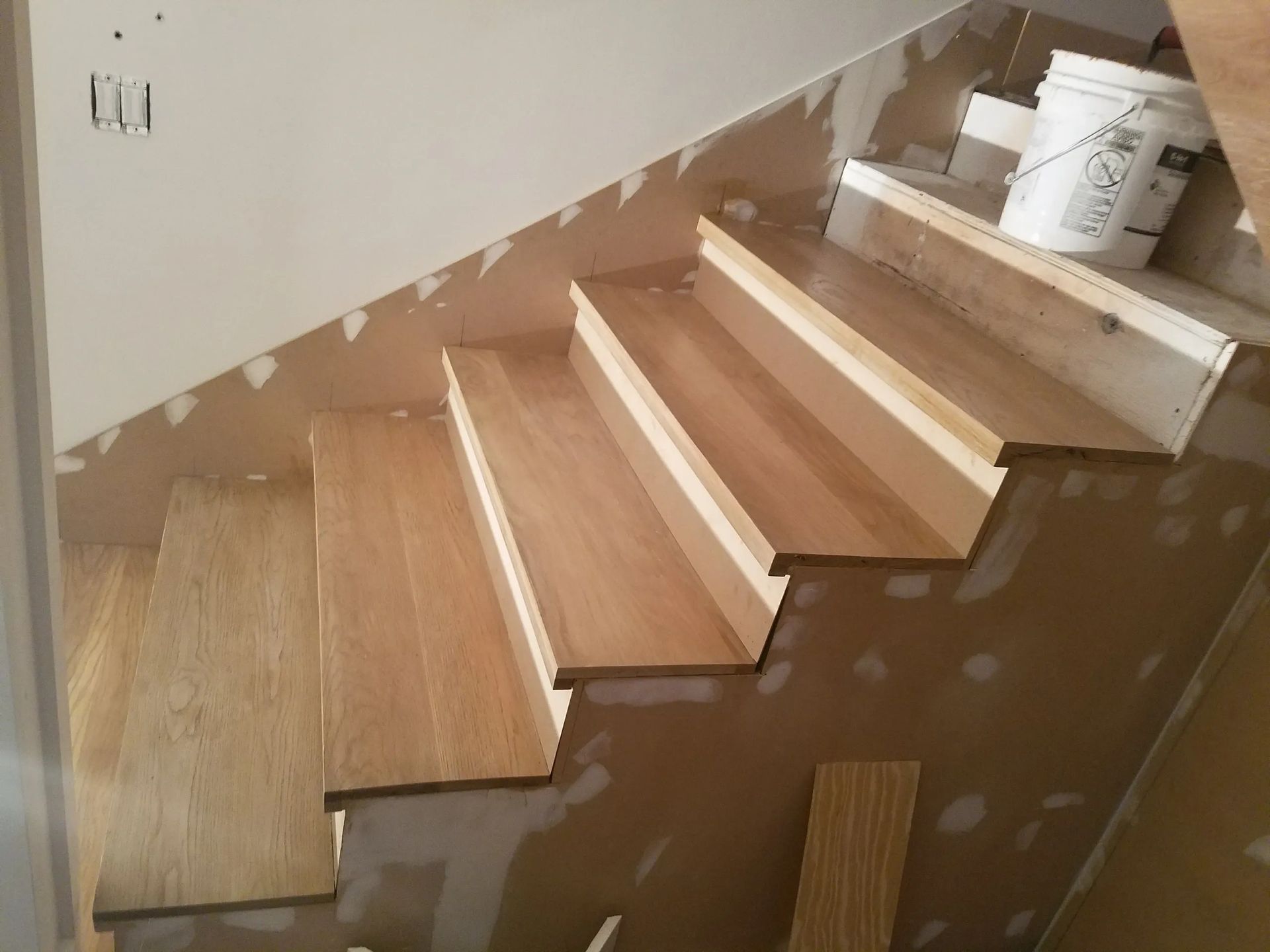 A wooden staircase with a bucket of paint on the bottom shelf
