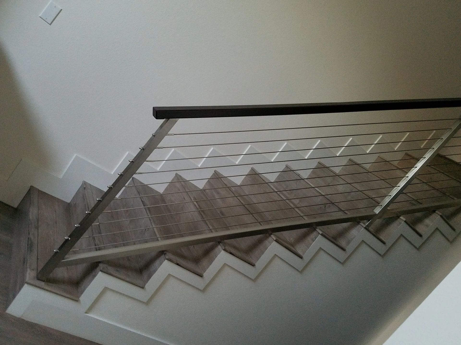 A staircase with a stainless steel railing and wooden steps