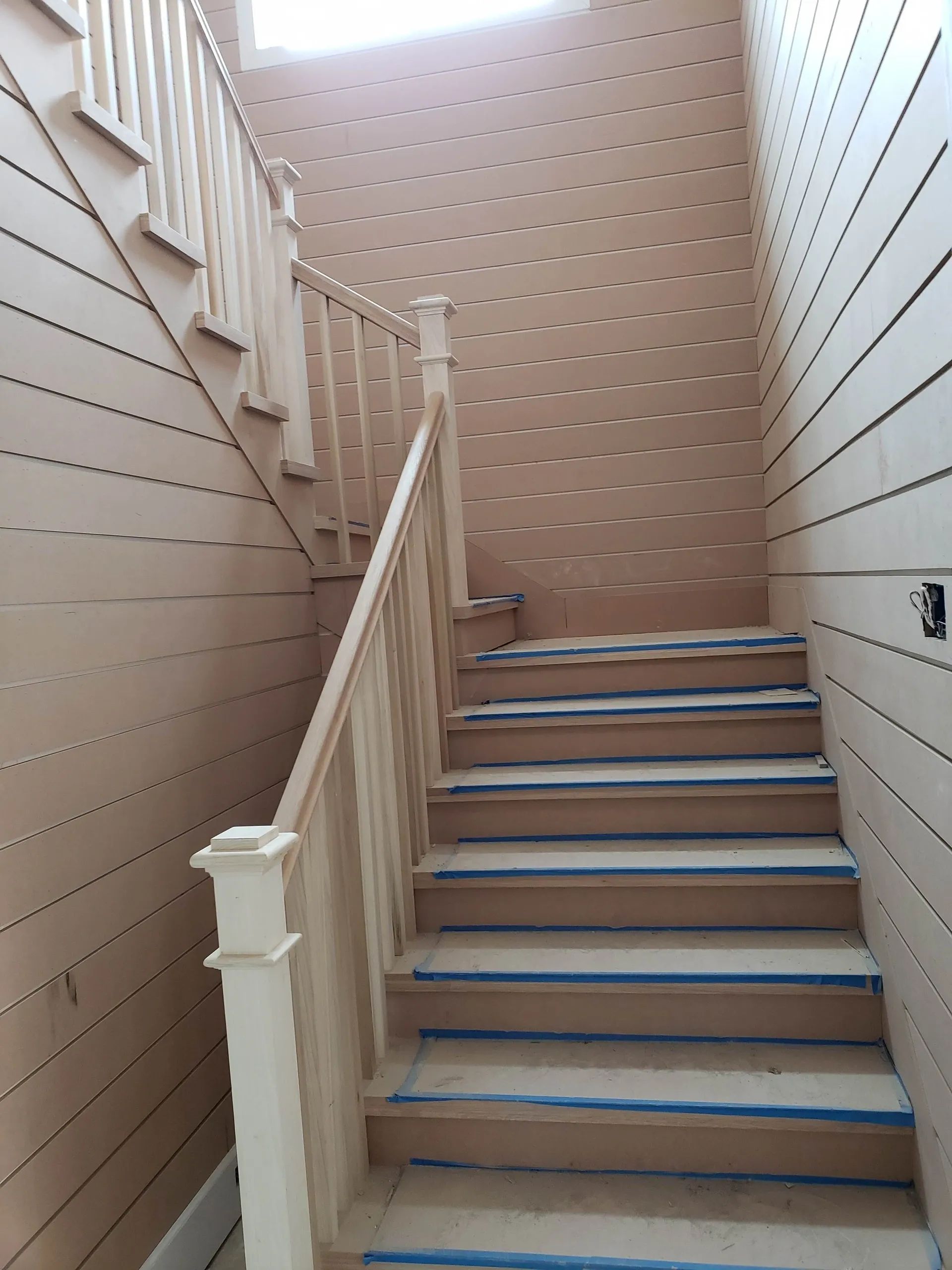 A staircase with a white railing and blue tape on the steps