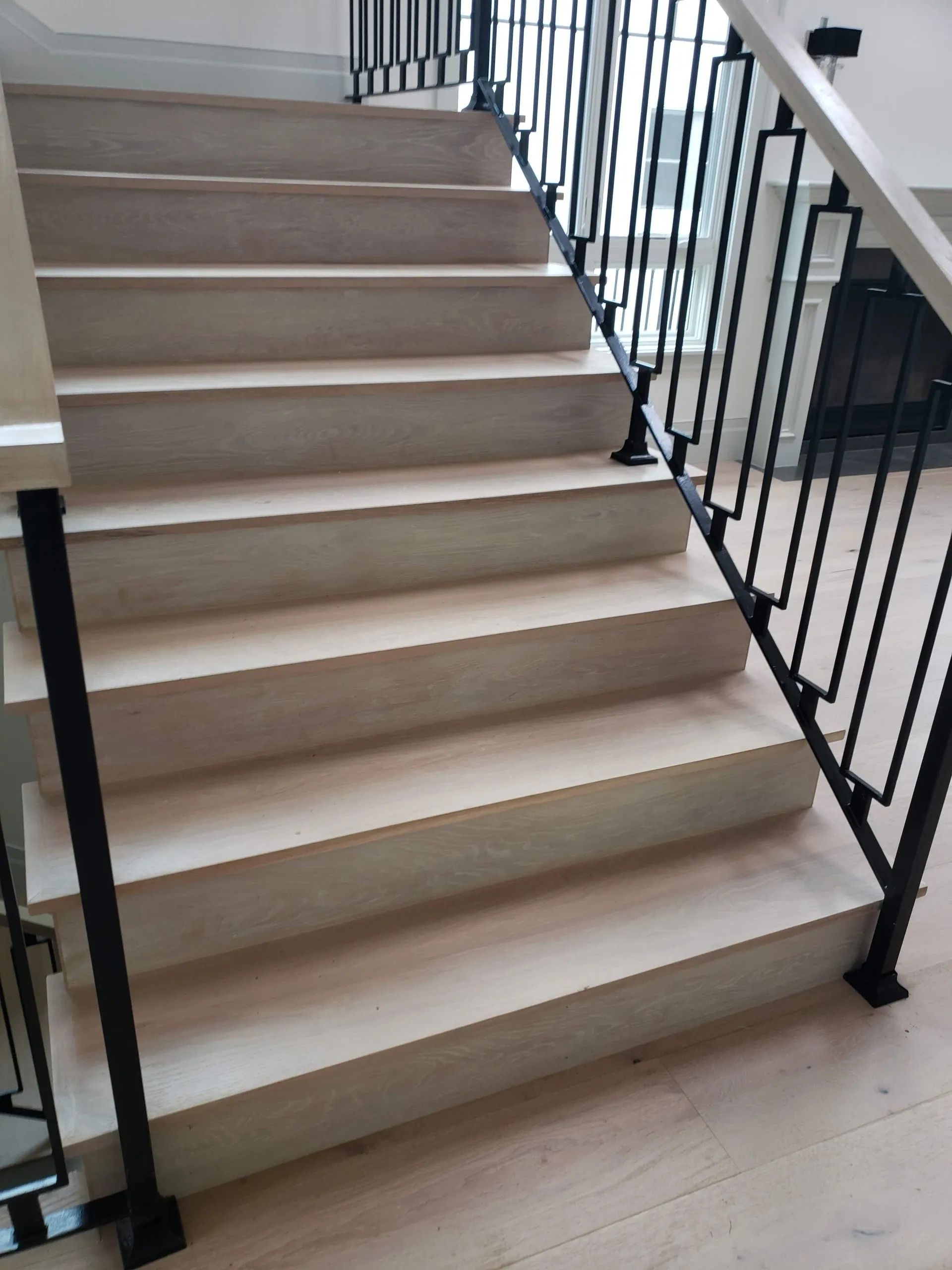 A set of stairs with a black railing and a wooden floor