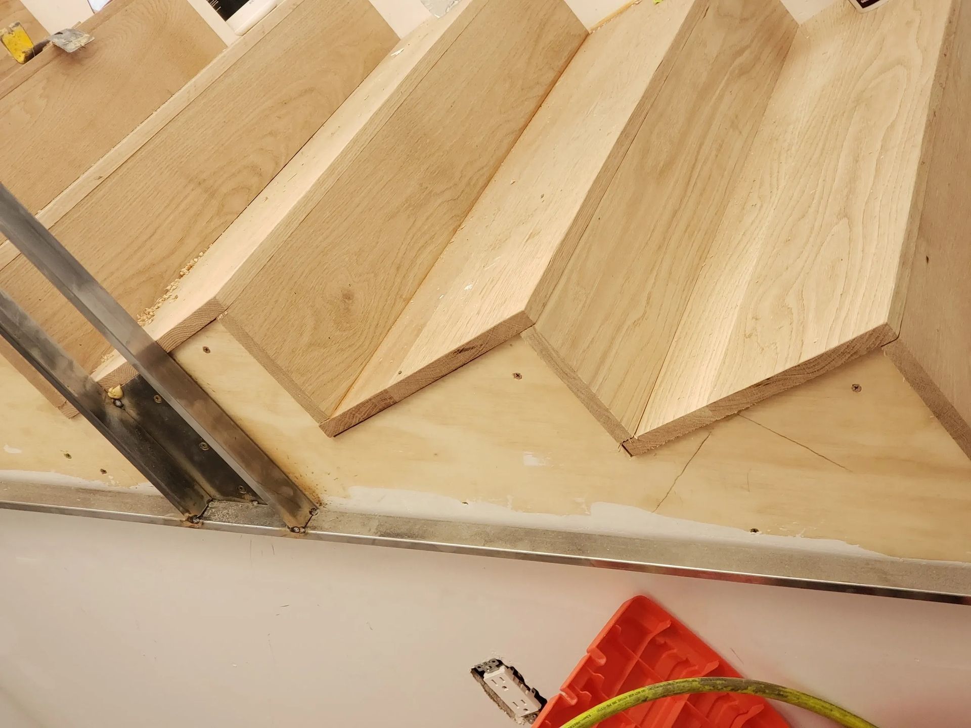 A close up of a wooden staircase with a measuring tape on the floor