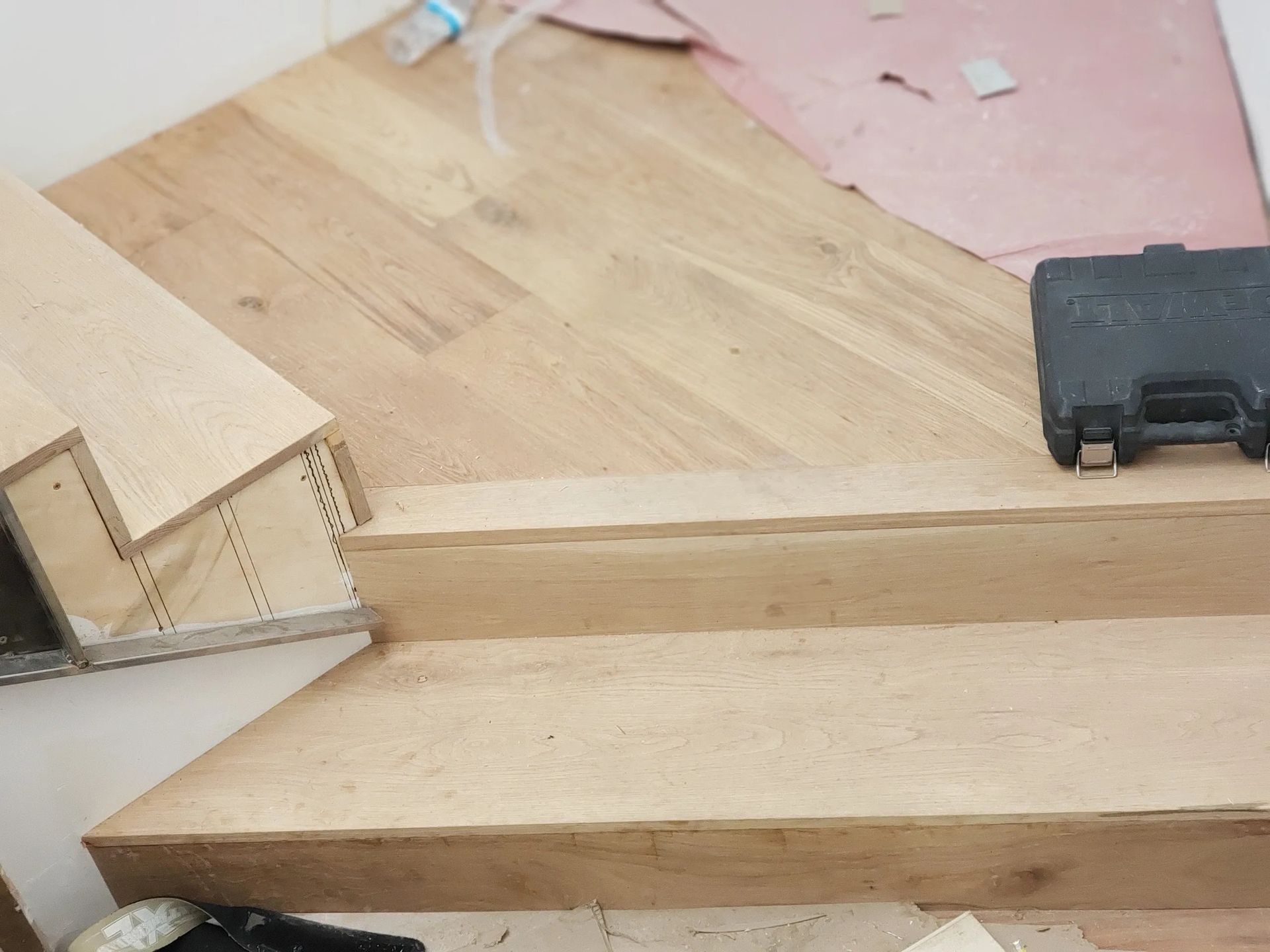 A wooden staircase is being built with a toolbox on the floor