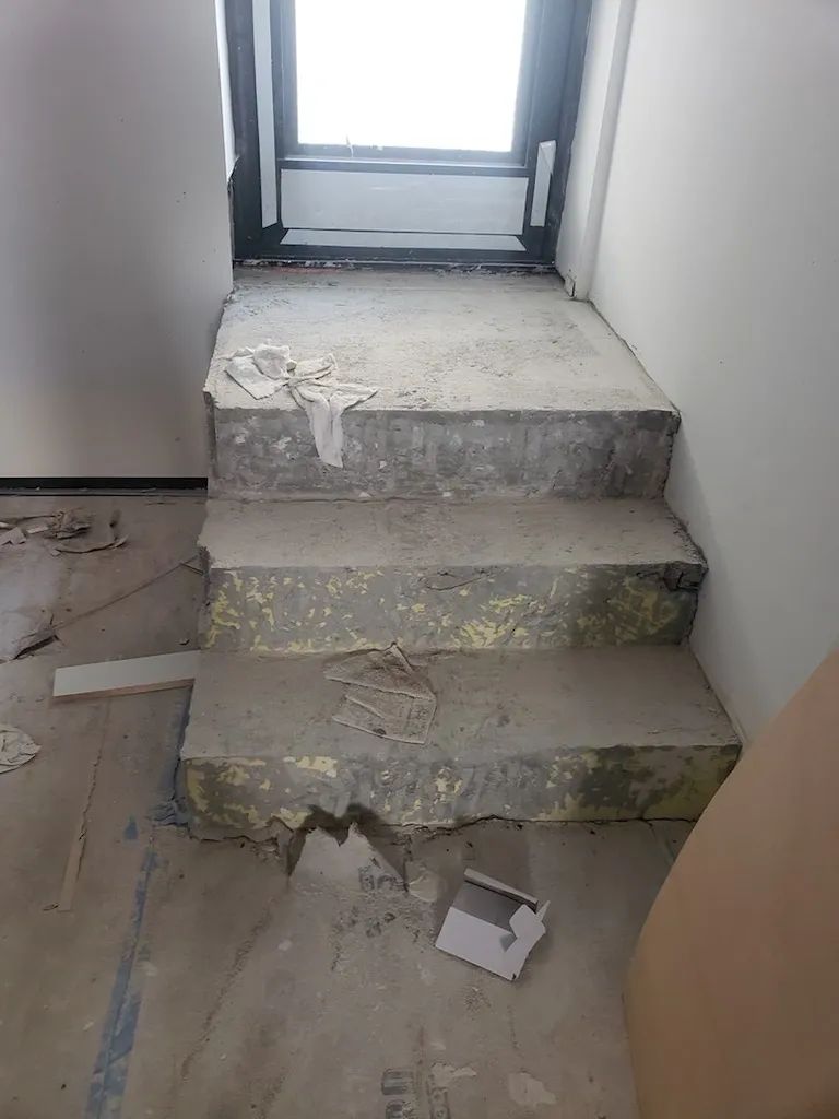 A broken concrete staircase in a room with a window