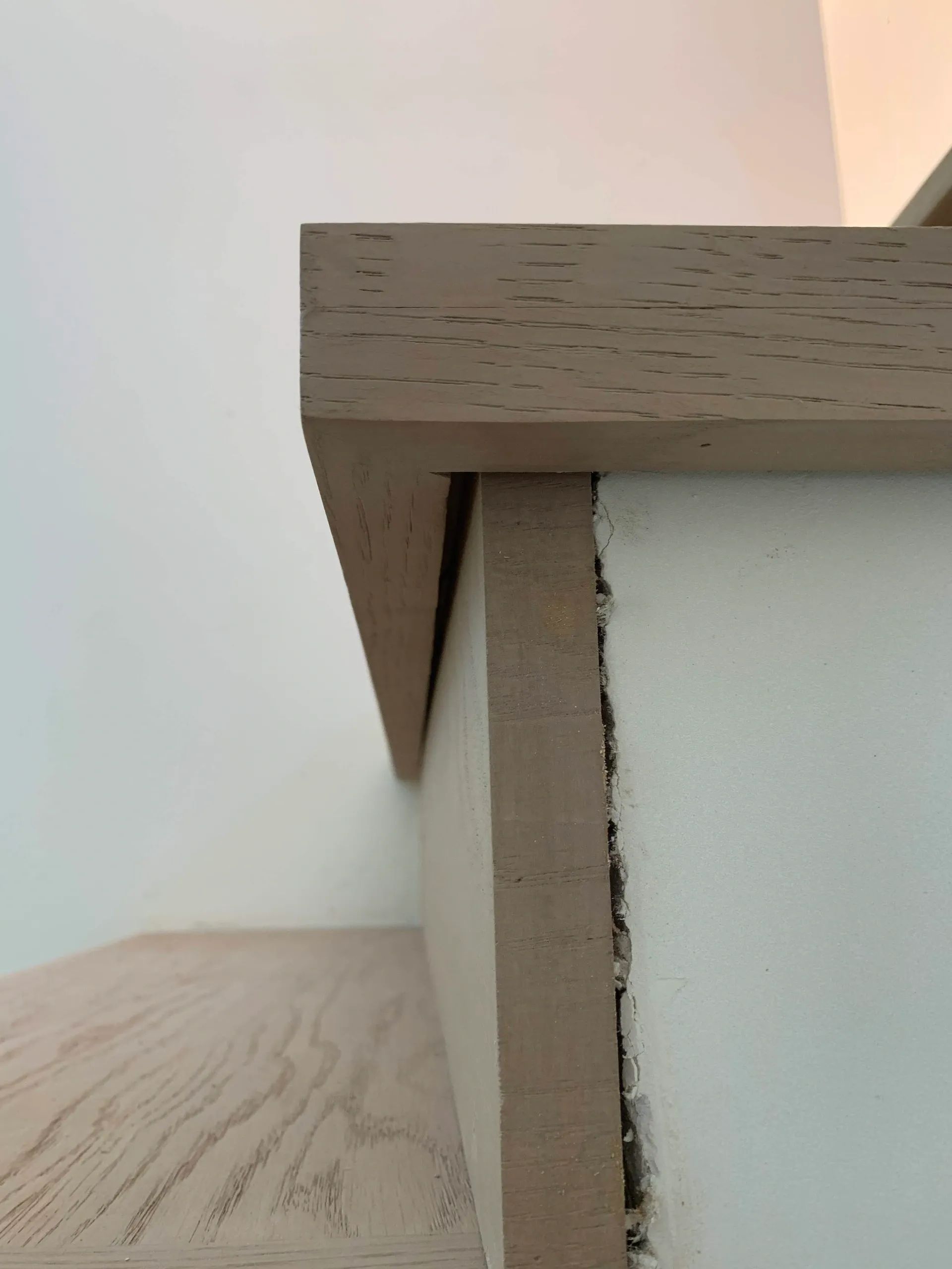 A close up of a wooden shelf with a white wall in the background