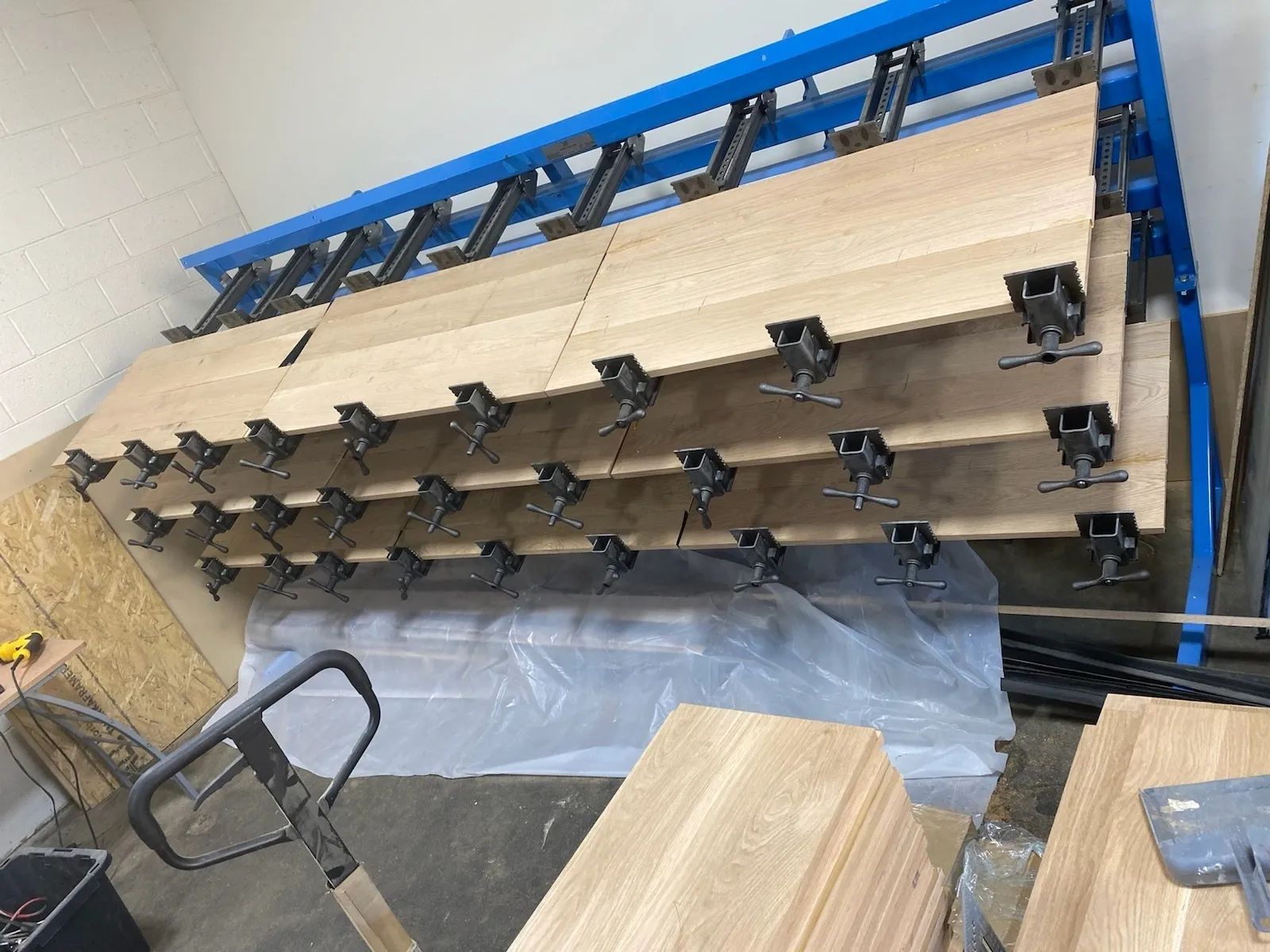 A pallet truck is carrying a stack of wooden shelves in a room
