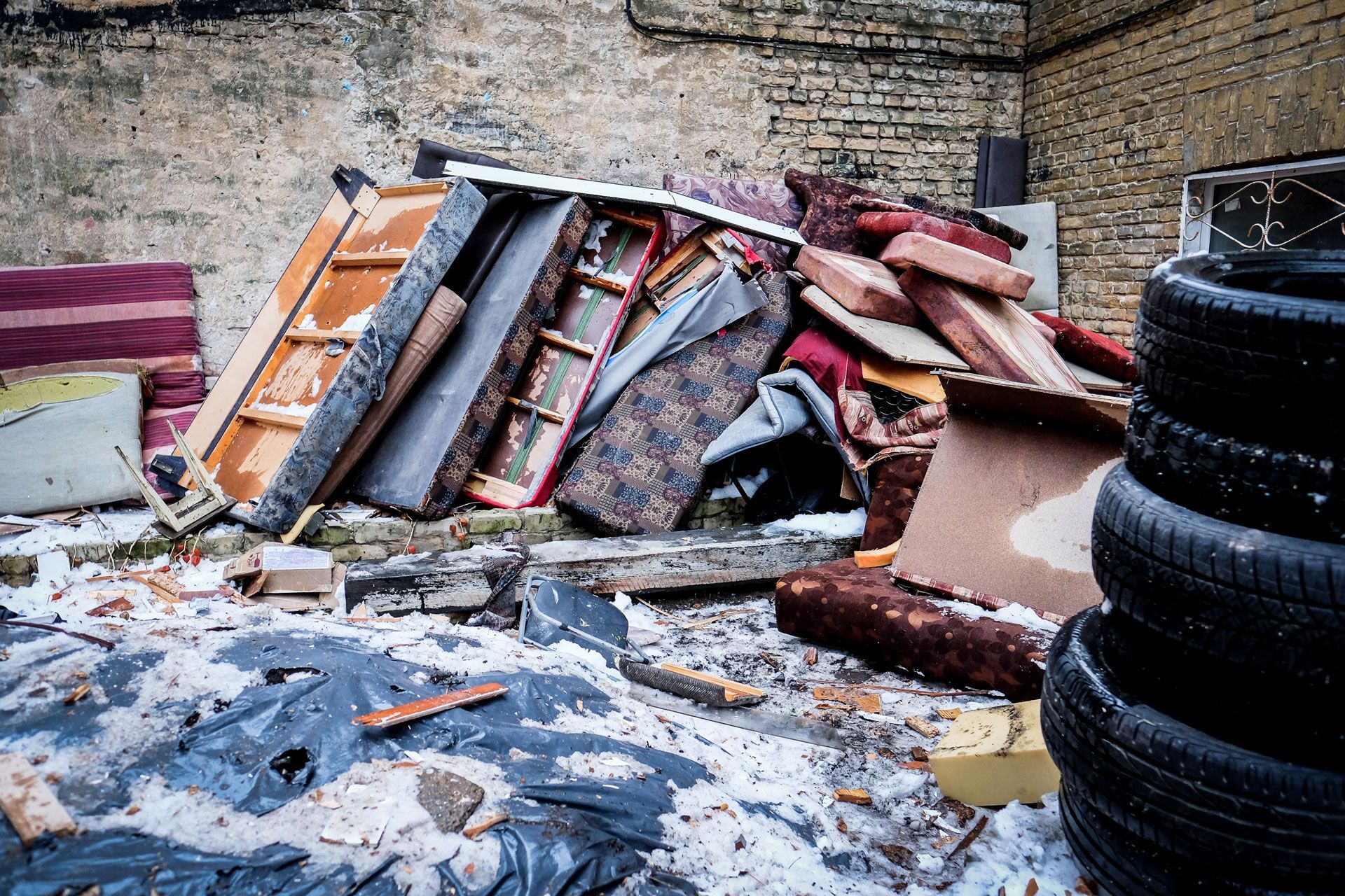A pile of trash is sitting in front of a brick building.