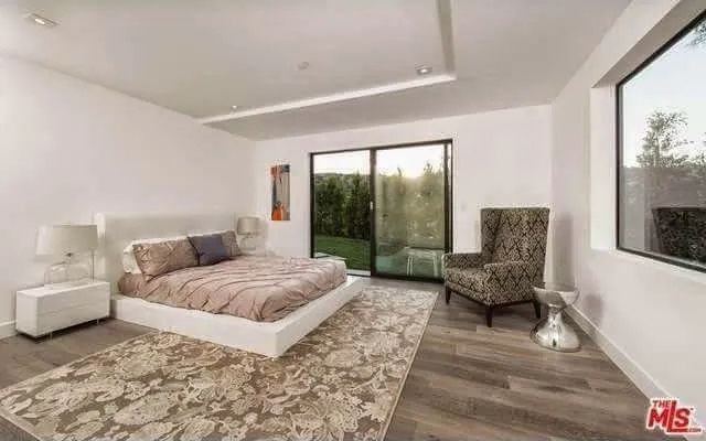 A bedroom with a large bed, chair, rug and window