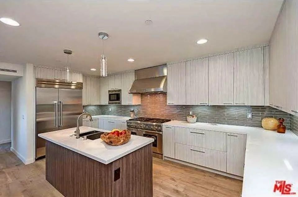 A kitchen with white cabinets, stainless steel appliance , and a large island
