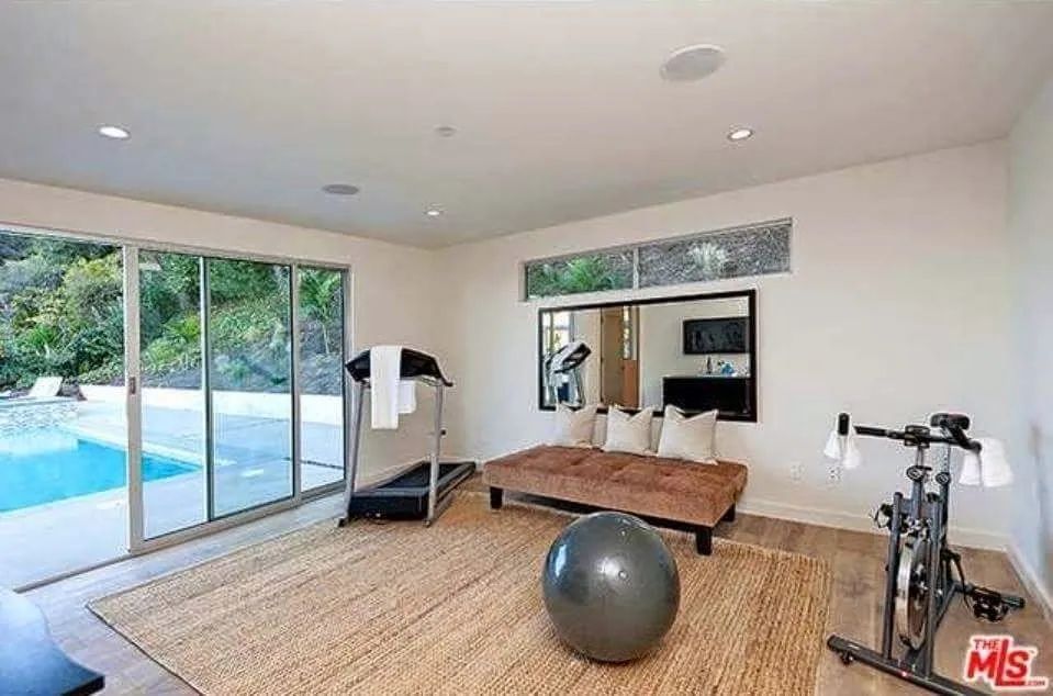 A living room with a couch, exercise ball, treadmill and a bicycle