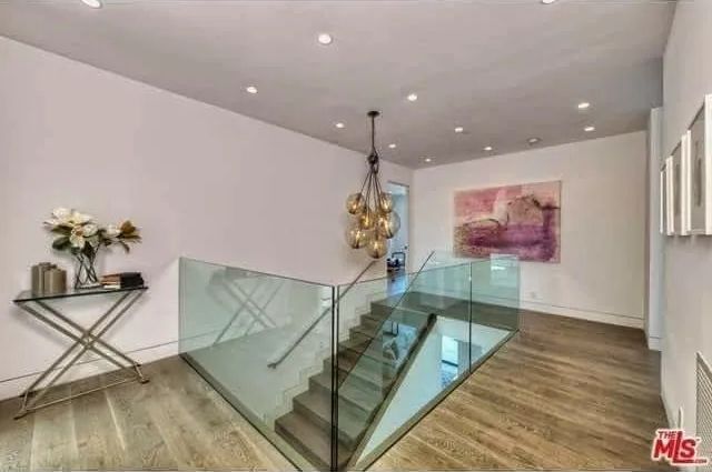 A staircase with a glass railing and a painting on the wall