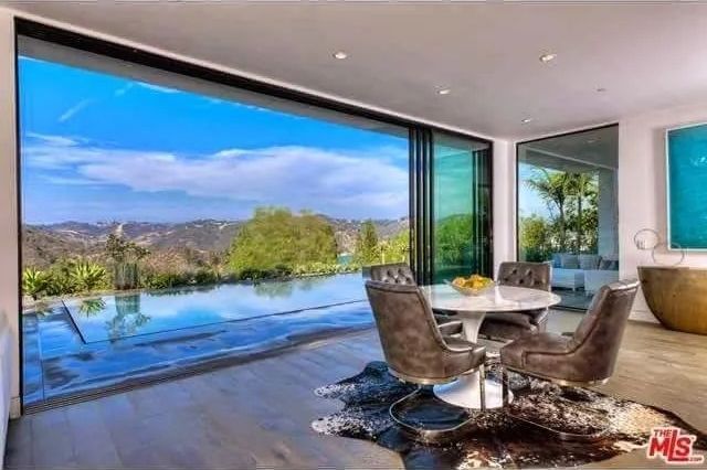 A dining room with a table and chairs and a view of a swimming pool