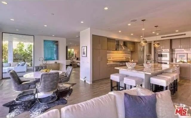 A living room with a couch, chairs, a table and a kitchen