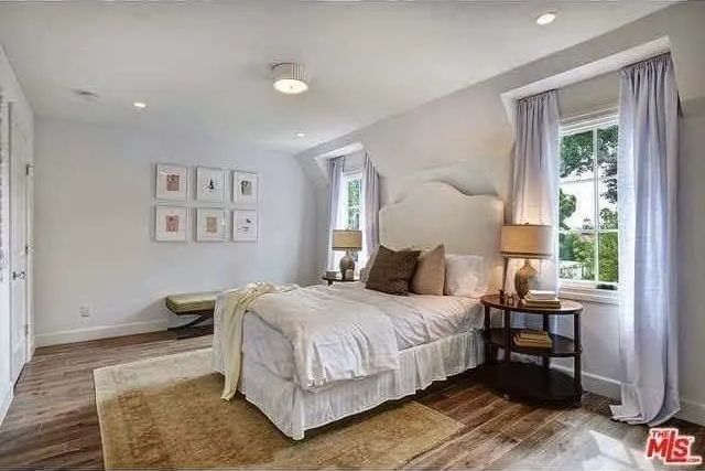 A bedroom with a bed , nightstand , lamps and a window