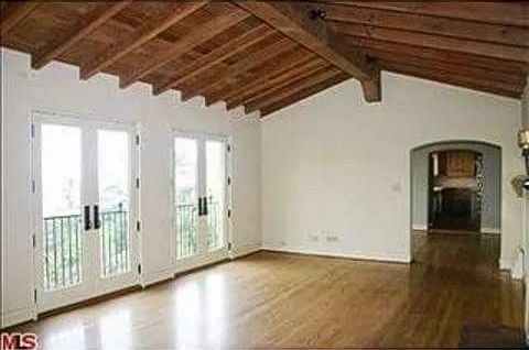 An empty living room with hardwood floors and a wooden ceiling