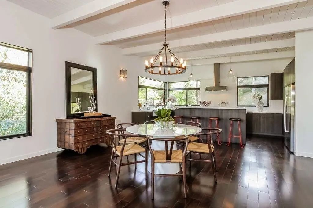 A dining room with a round table and chairs and a chandelier hanging from the ceiling