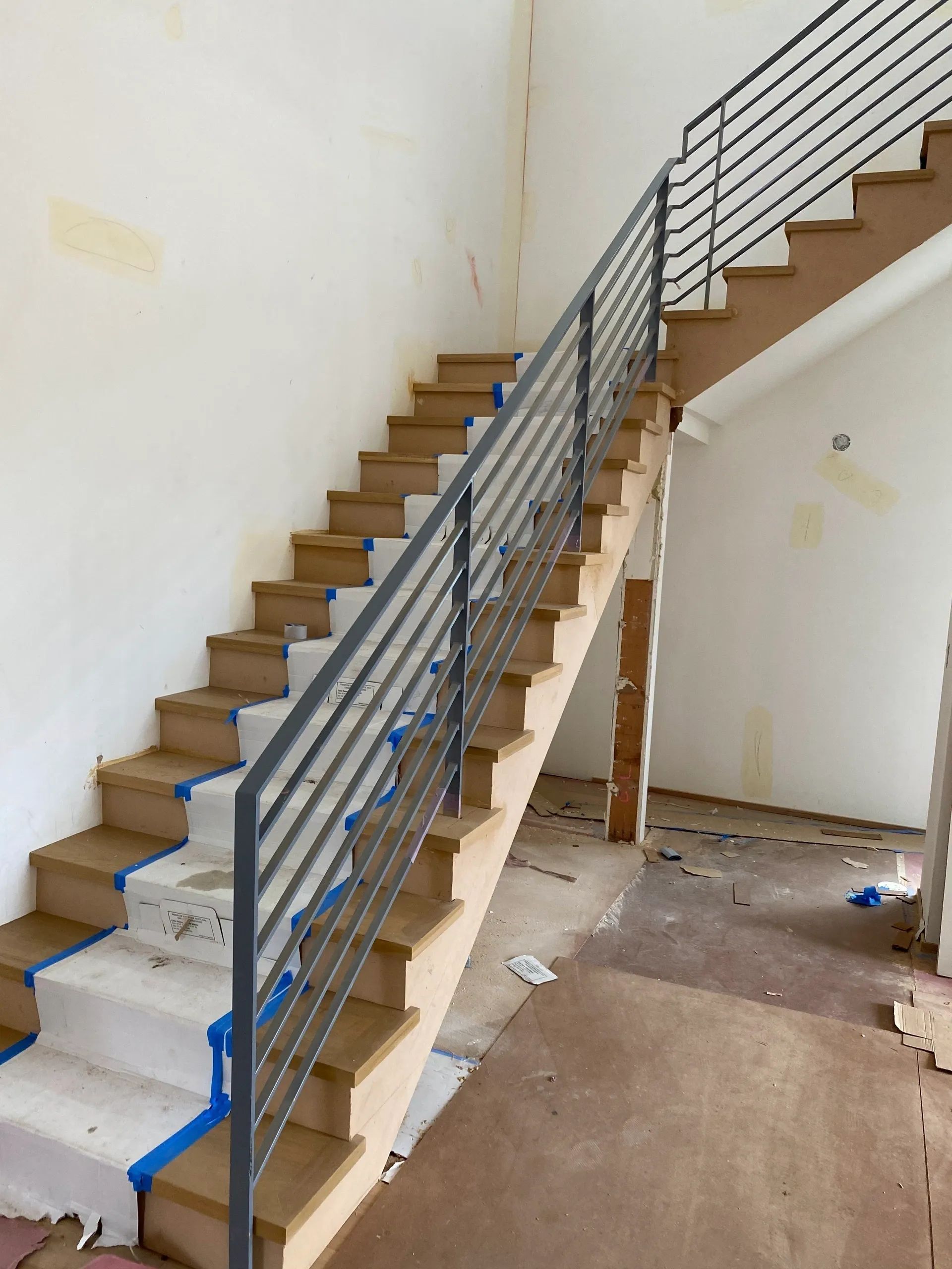 A wooden staircase with a metal railing in a room