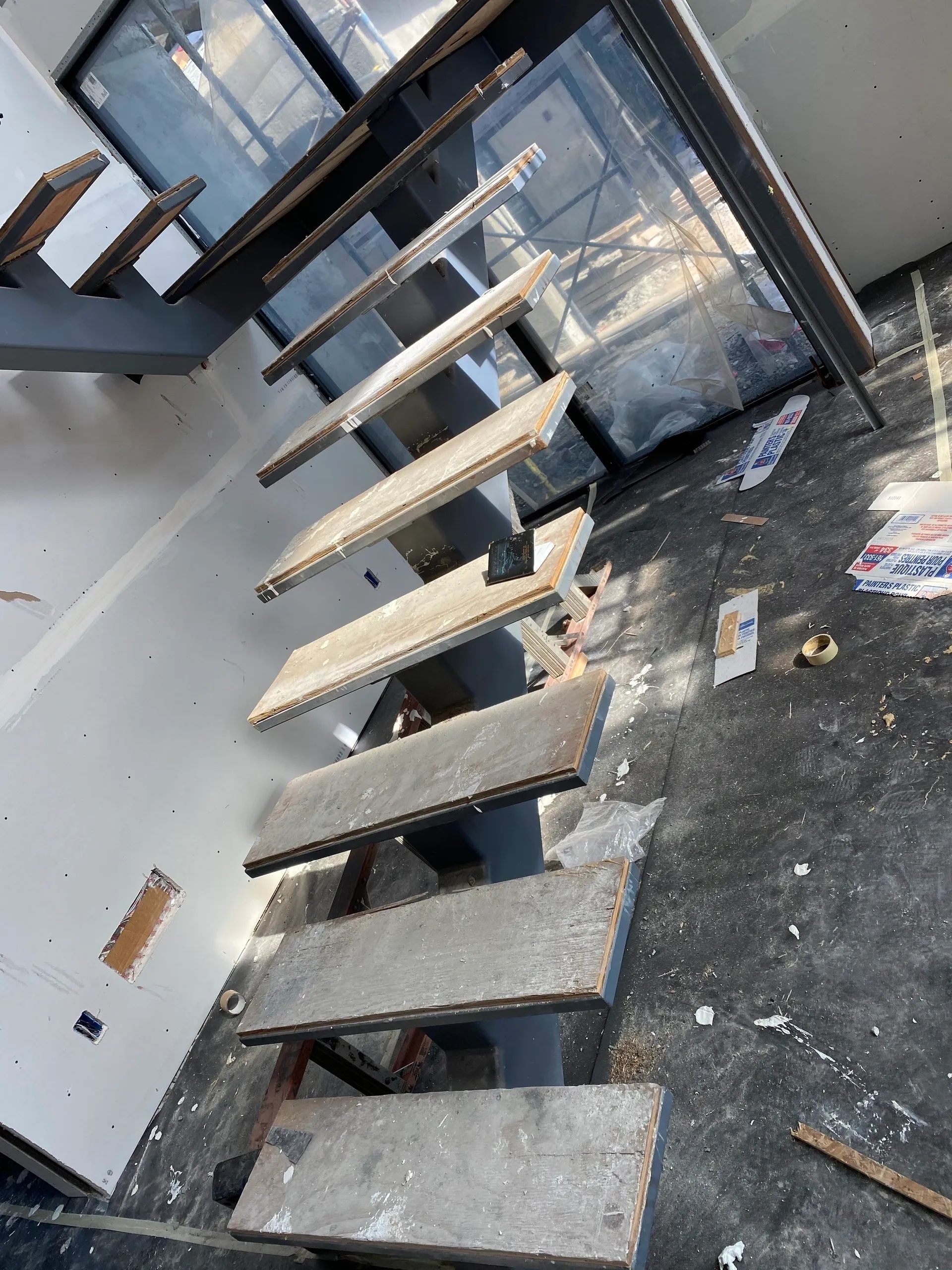 A staircase is being built in a room with a lot of trash on the floor