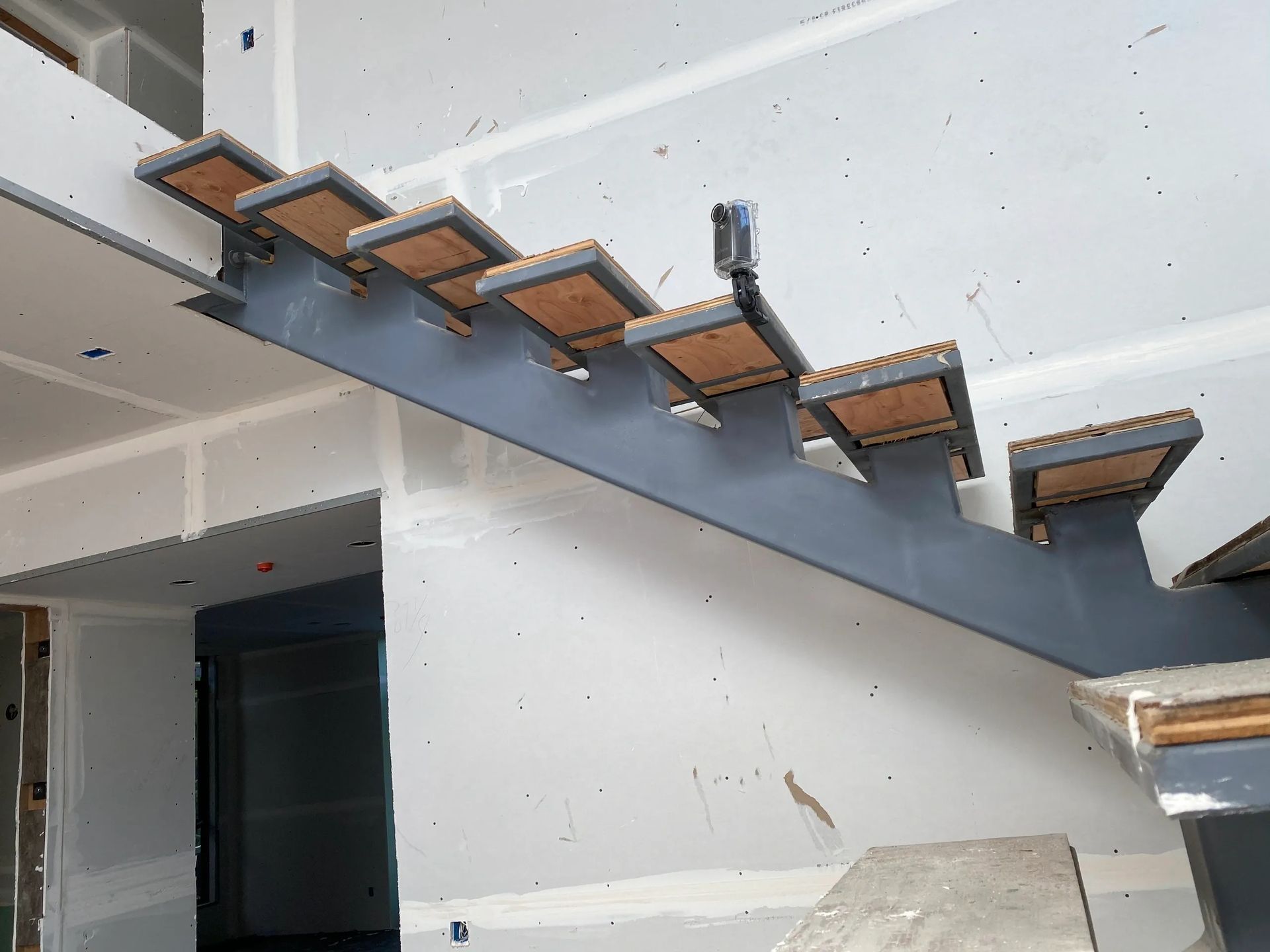 A metal staircase with wooden steps is being built in a house