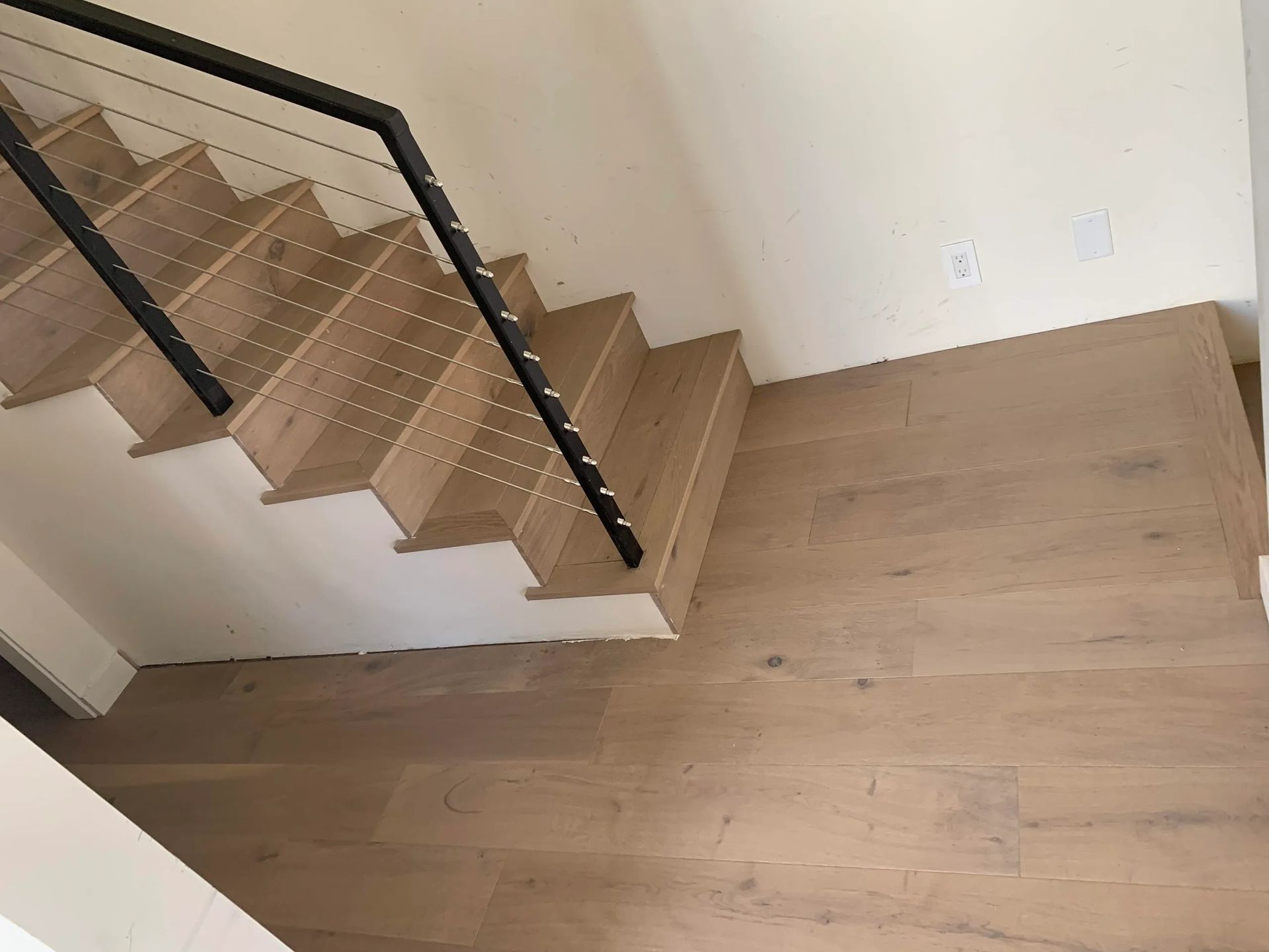 A wooden staircase with a black railing in a room