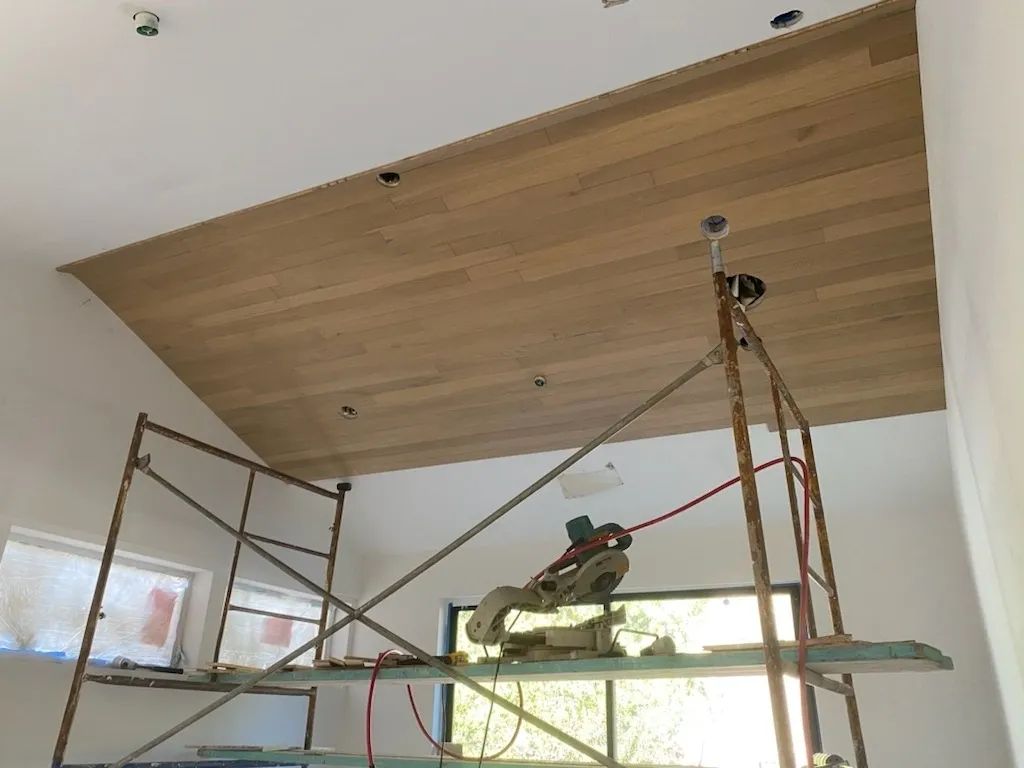 A person is working on a wooden ceiling in a room
