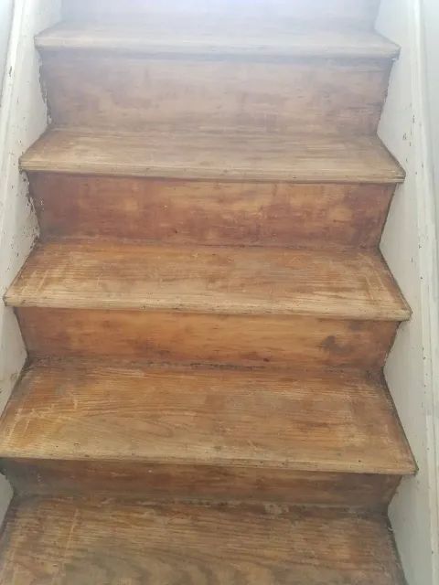 A close up of a wooden staircase with a white railing