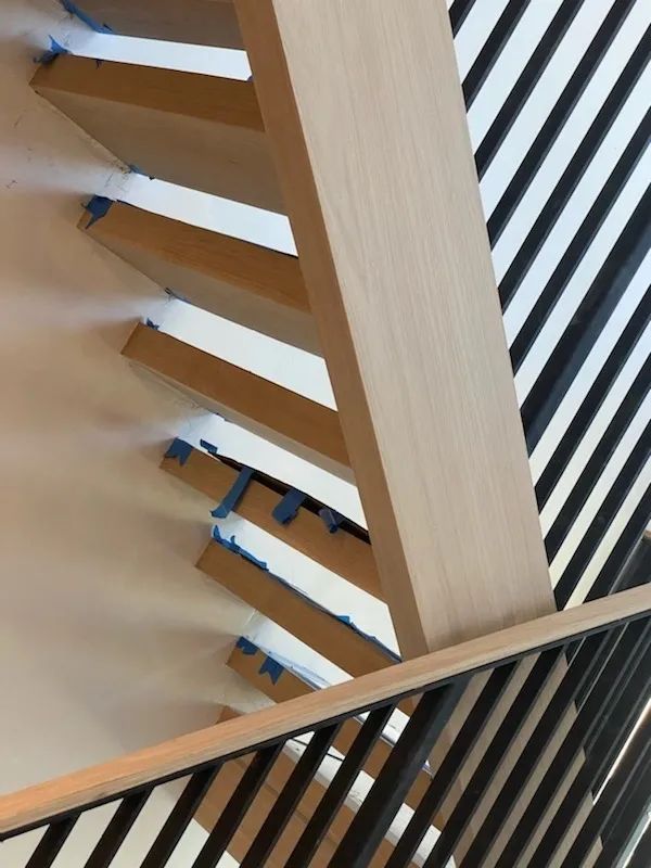 A wooden staircase with a black and white striped railing