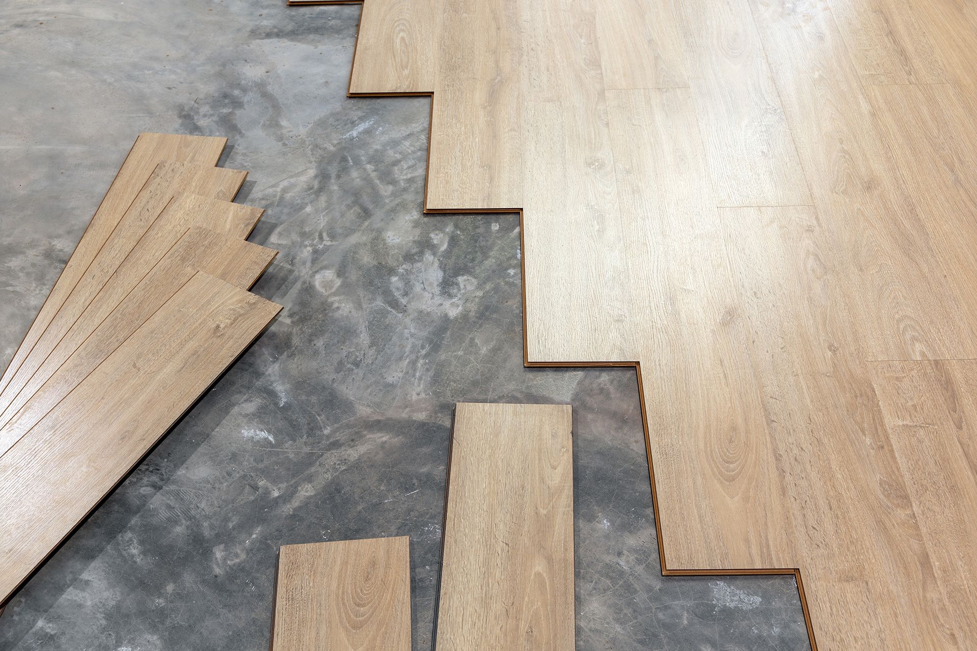 A wooden floor is being installed on a concrete floor.