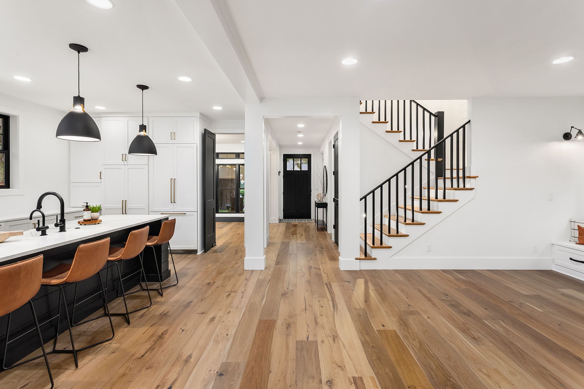 A kitchen with hardwood floors and a staircase leading up to the second floor.