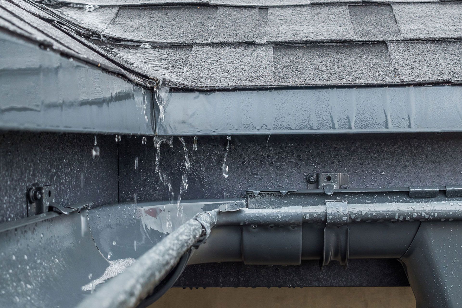 Jets of rain drain into the drainage system on the roof of the house