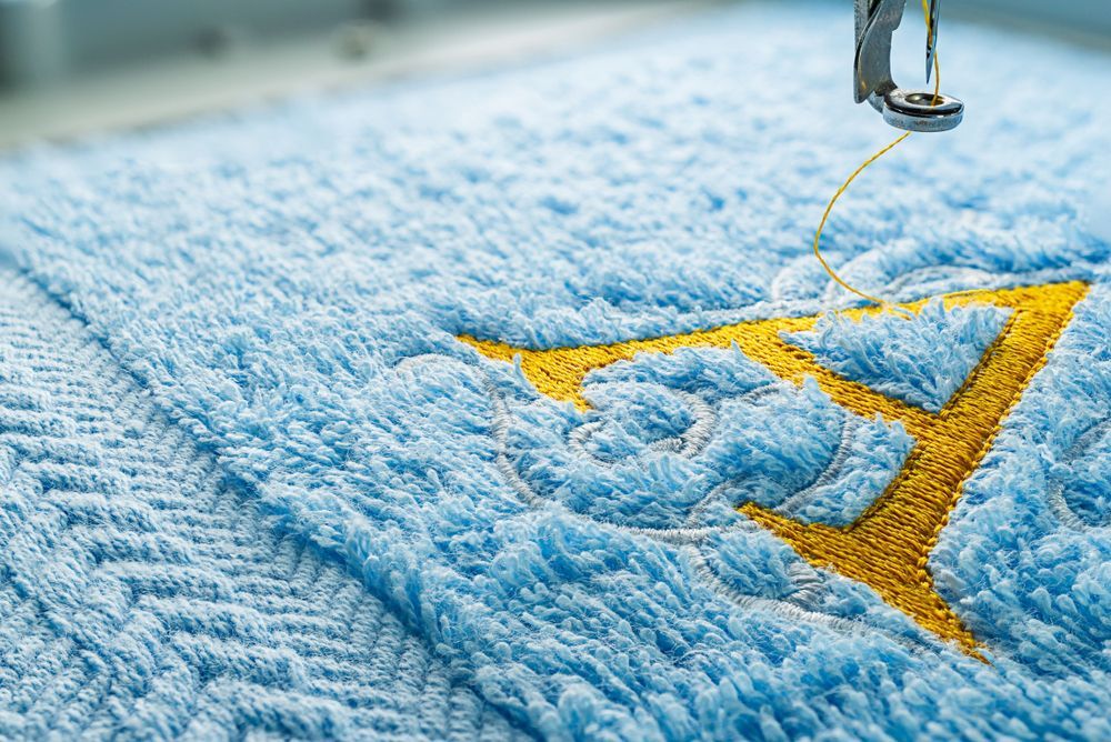 A Close Up Of A Sewing Machine Embroidery On A Blue Towel — Sew Affordable In Charmhaven, NSW