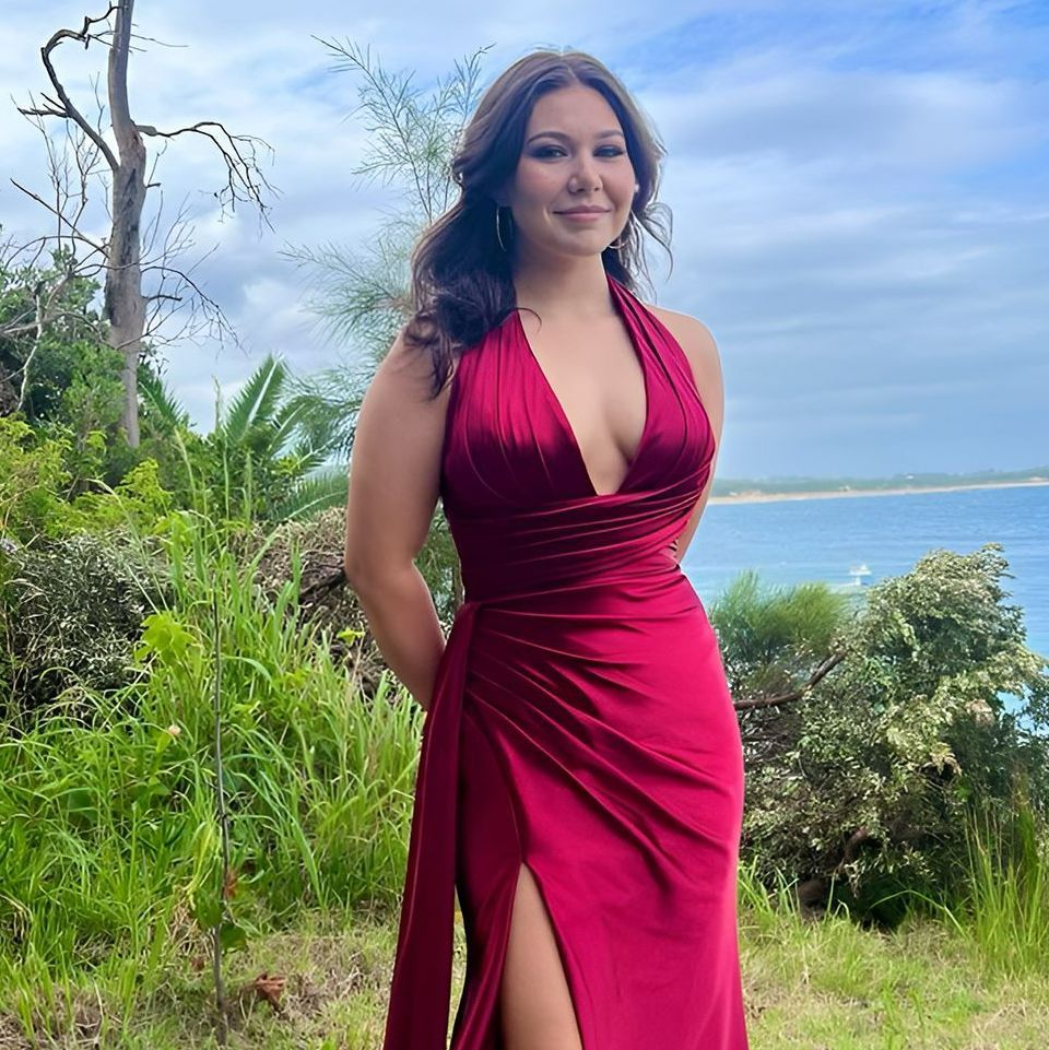 A Woman In A Red Dress Is Standing In Front Of A Body Of Water — Sew Affordable In Charmhaven, NSW
