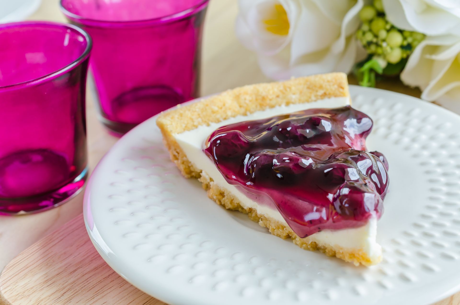 A slice of blueberry cheesecake is on a white plate.