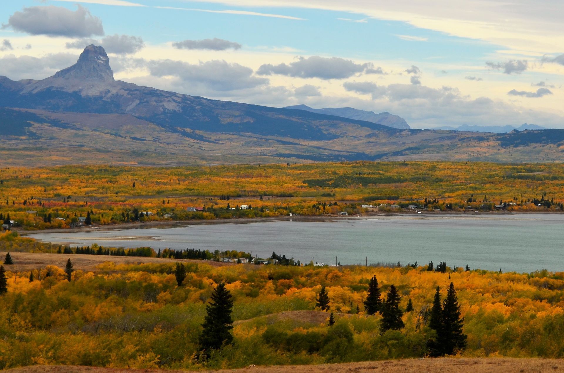 A lake surrounded by trees and mountains with a mountain in the background.