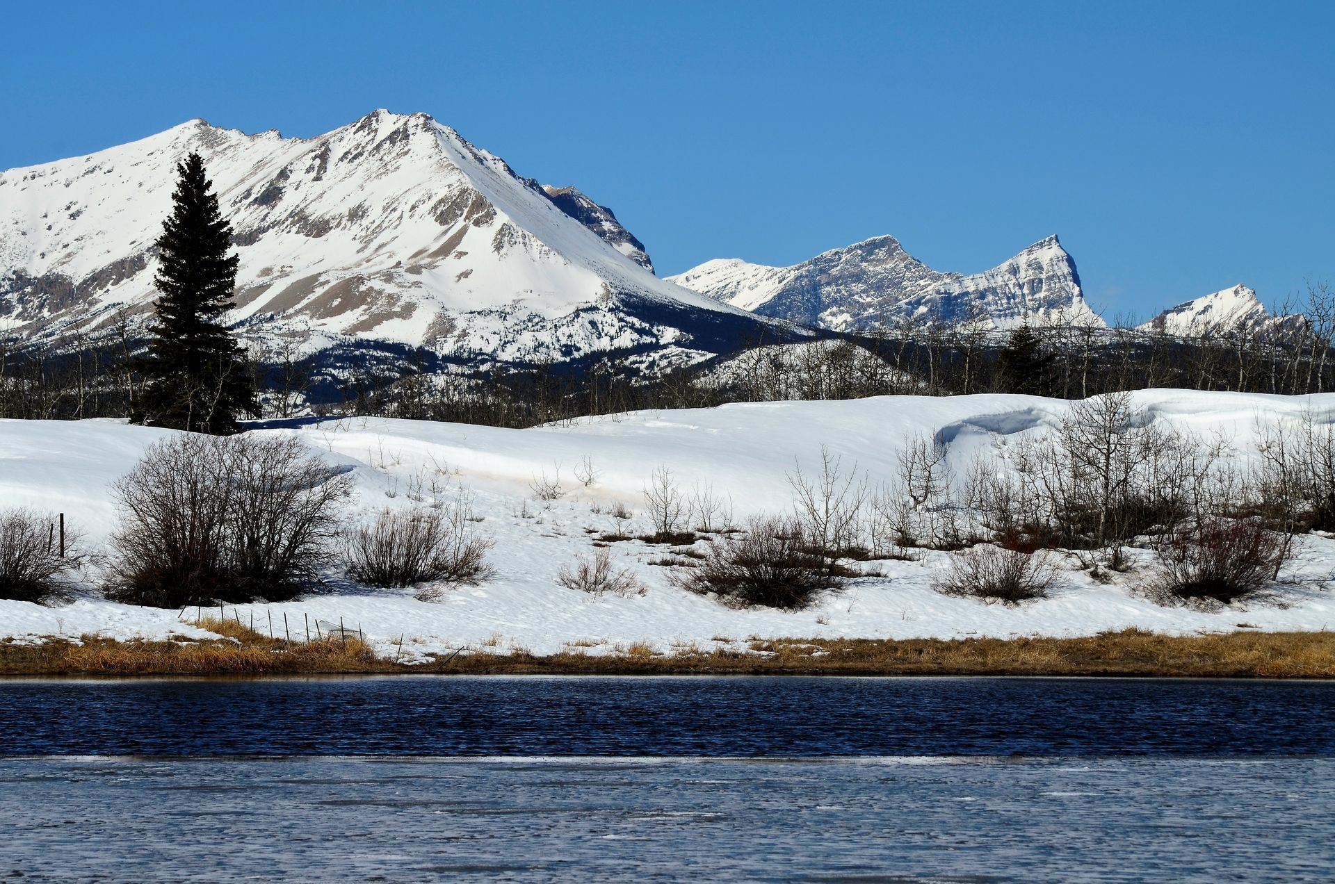 A snowy landscape with mountains in the background and a lake in the foreground