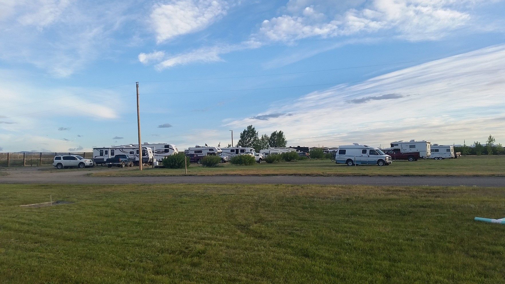 A group of rvs are parked in a grassy field next to a road.icon