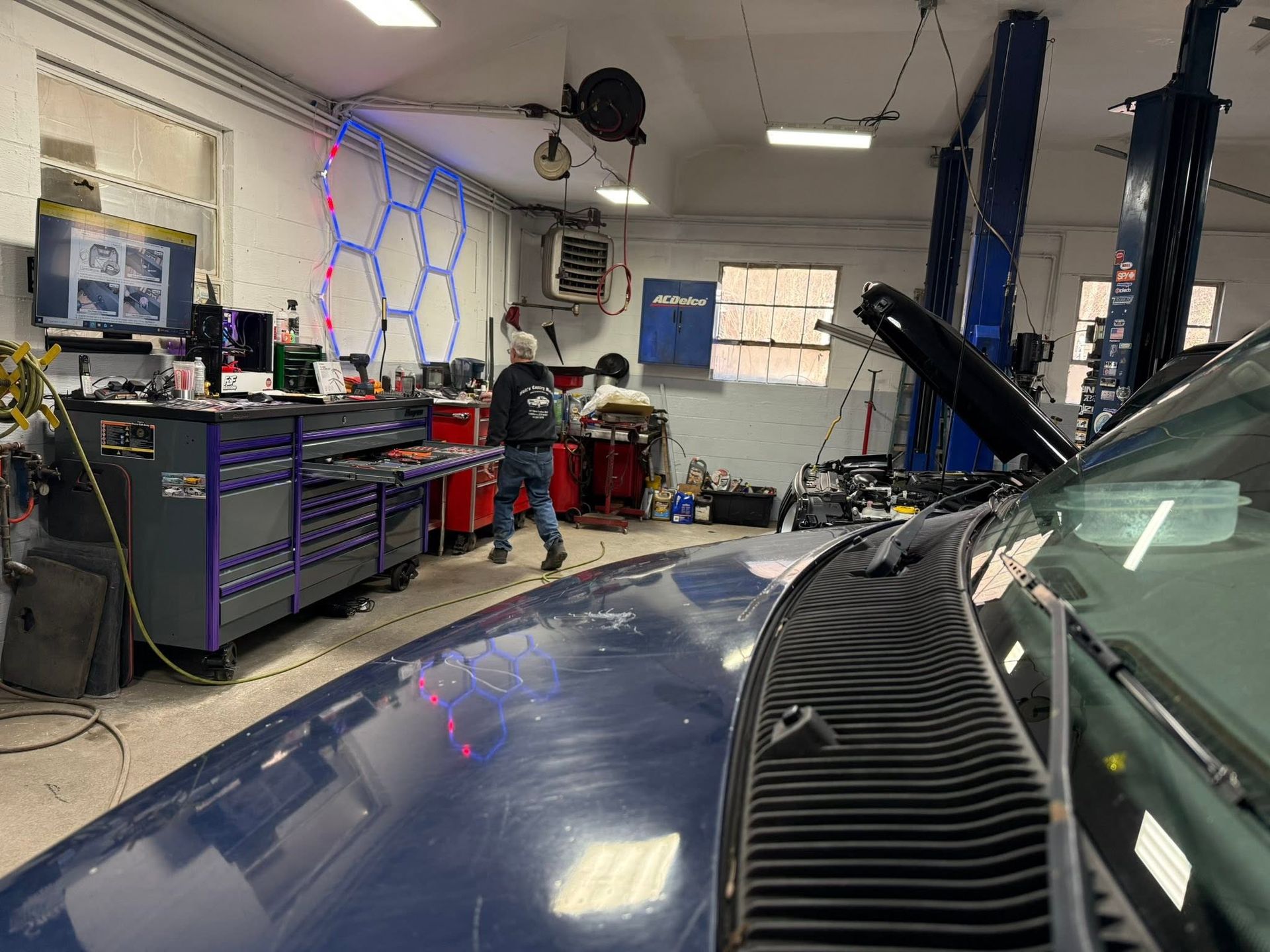 Auto repair shop with a blue car, open hood, and tools on a mechanic’s bench.