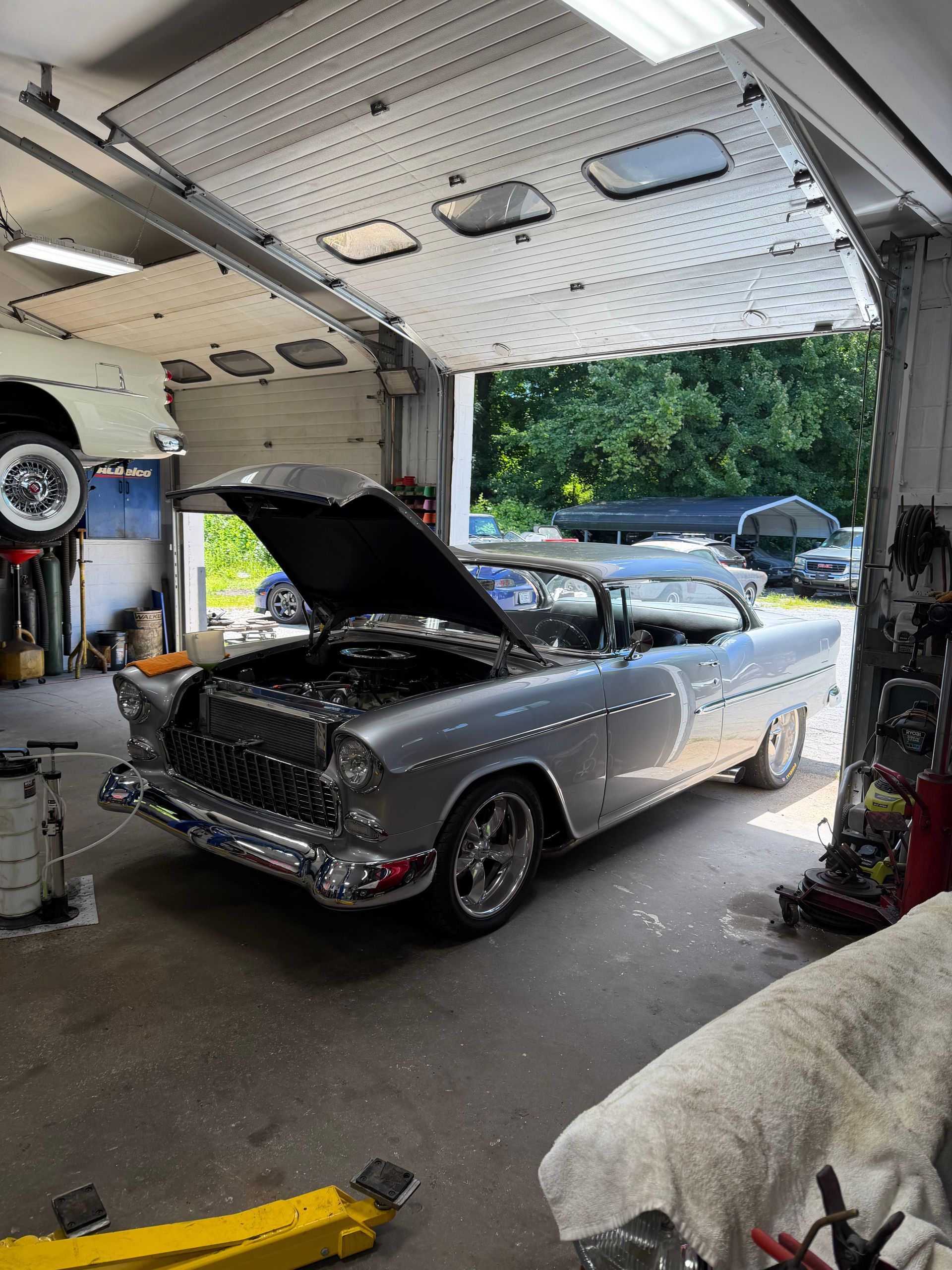 Silver classic car with hood open in a garage workshop