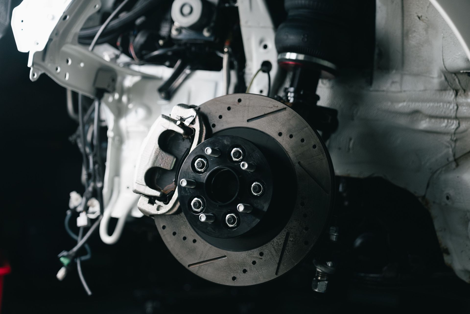 Close-up of a car brake rotor and hub assembly in a garage, with mechanical parts exposed