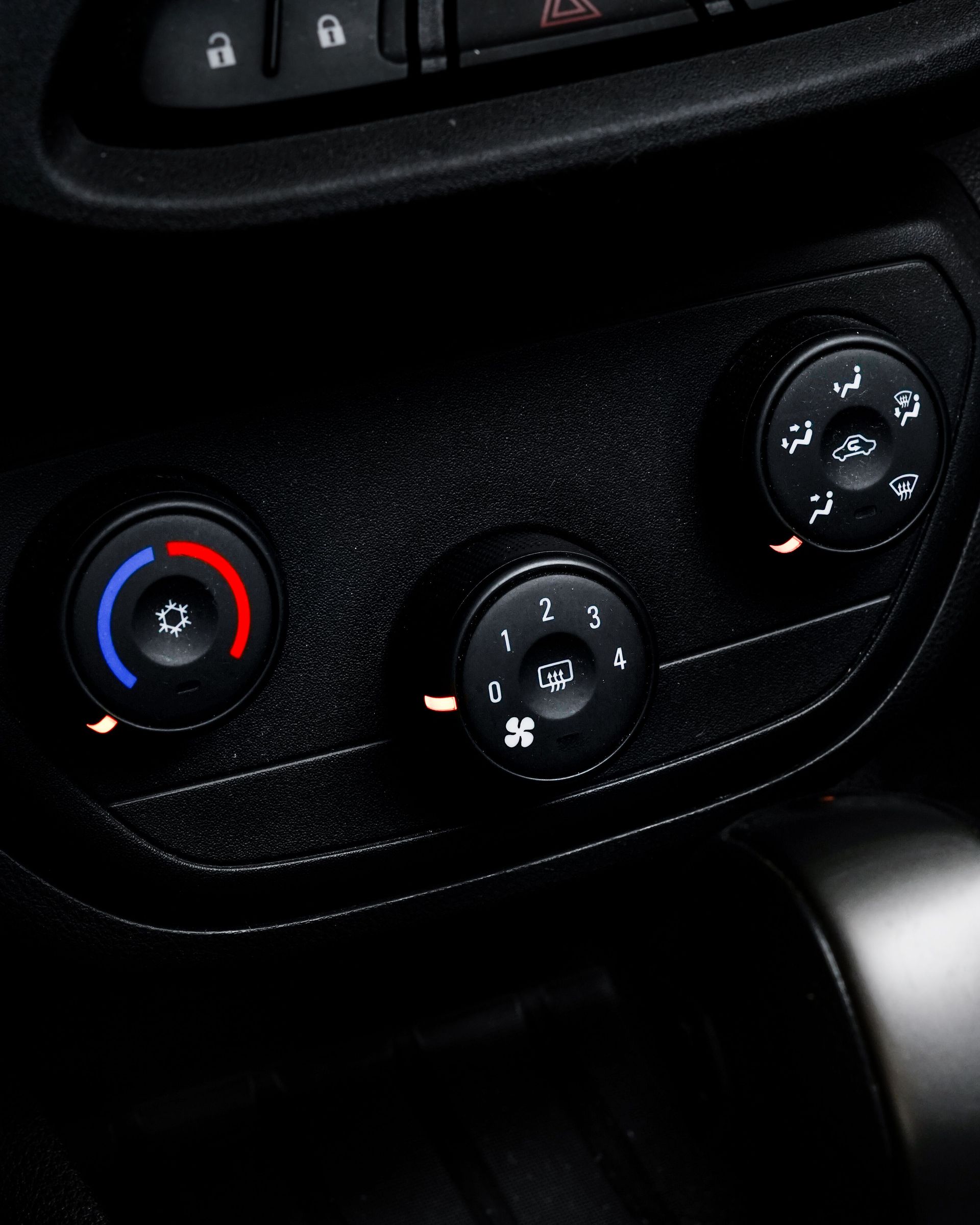 Car climate control panel with red and blue temperature dial and two fan control knobs