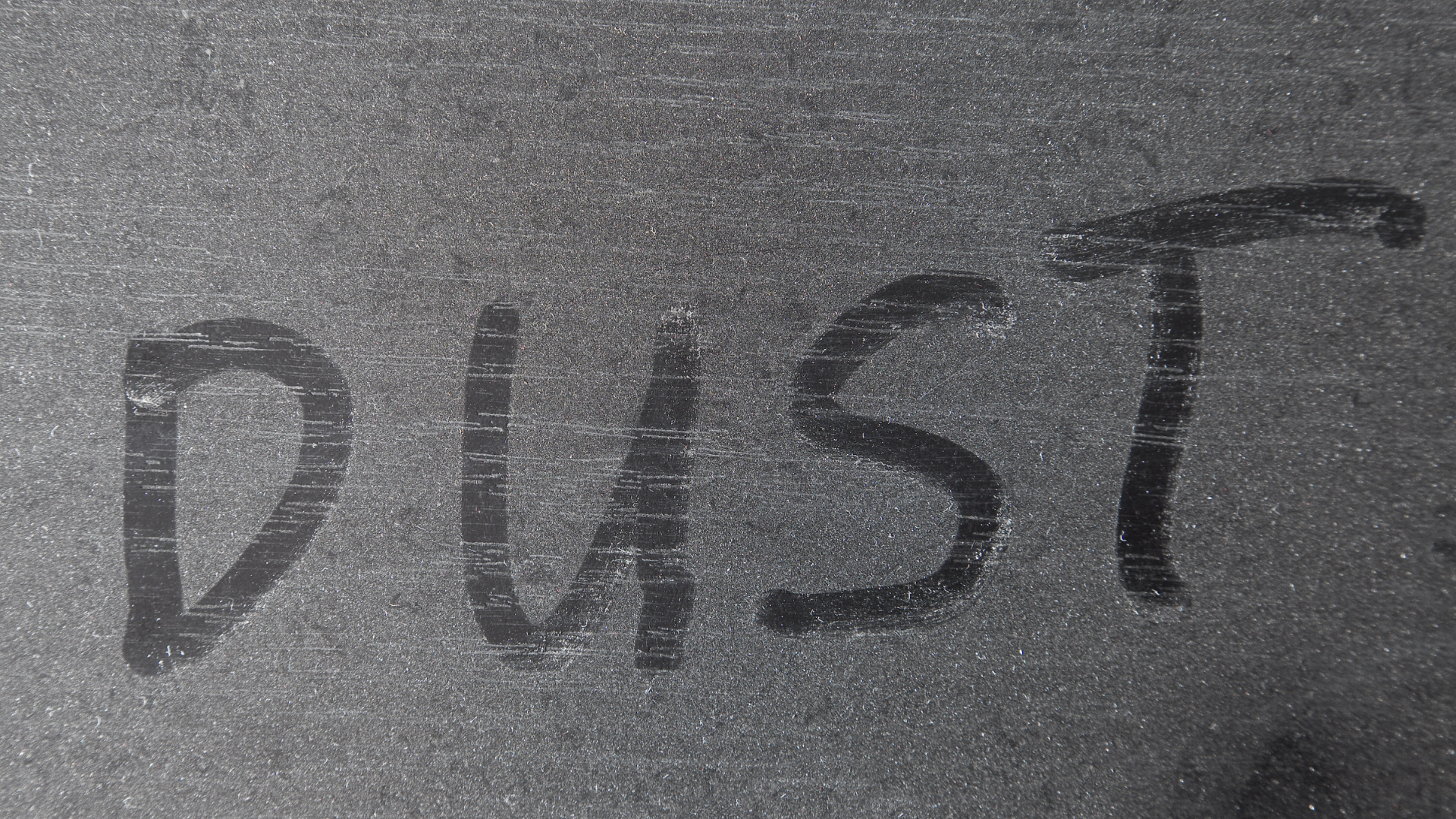 Dust written on a dusty, gray surface.