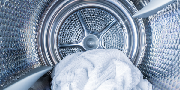 A pile of white clothes is sitting inside of a washing machine.